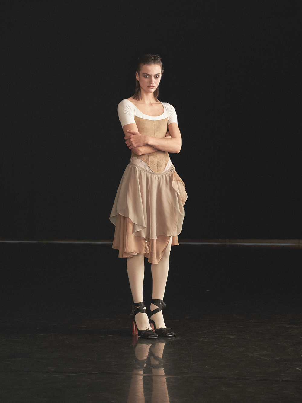 Maldire Alta Corsetteria campaign: dancer in a corset and draped skirt on a dark stage