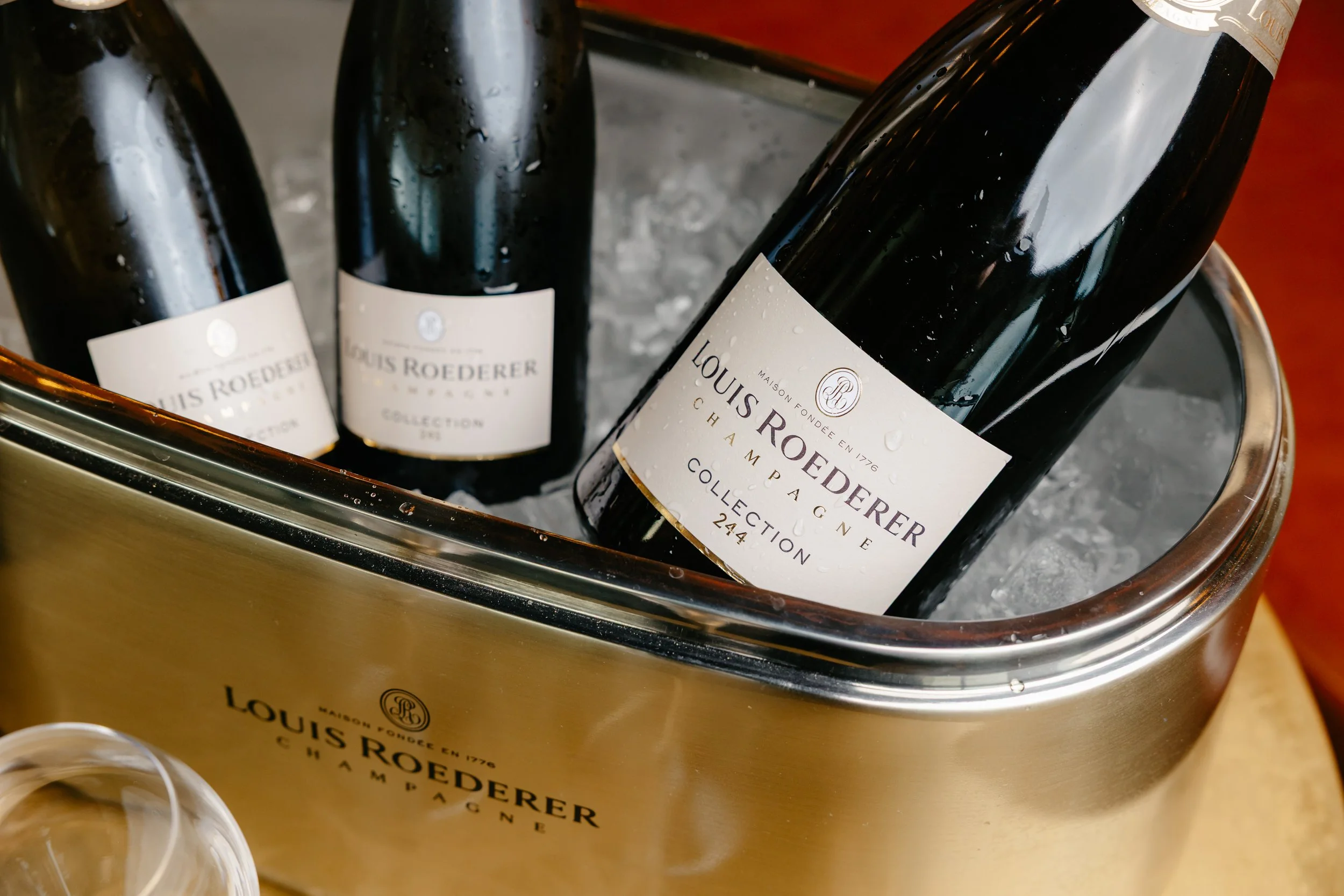 Three bottles of Louis Roederer Champagne in a metal ice bucket filled with ice