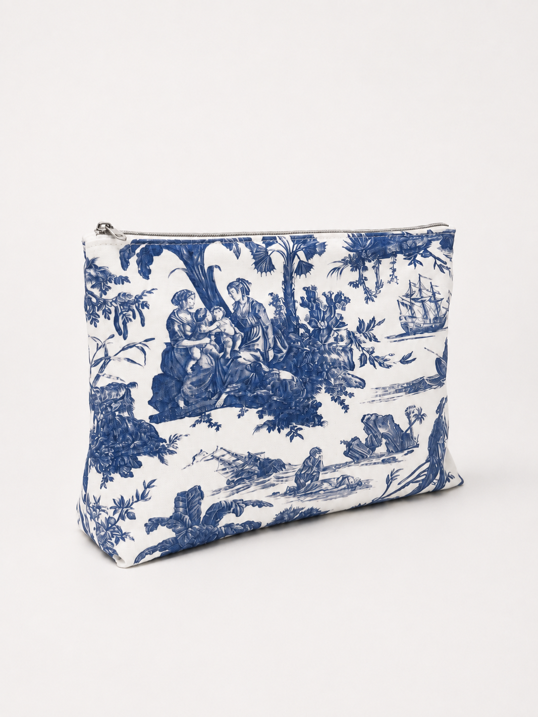 Sac en tissu blanc avec motif en bleu de style toile de Jouy représentant une scène pastorale avec des personnes sous des arbres, un bateau à voile sur l'eau, et des éléments de nature.
