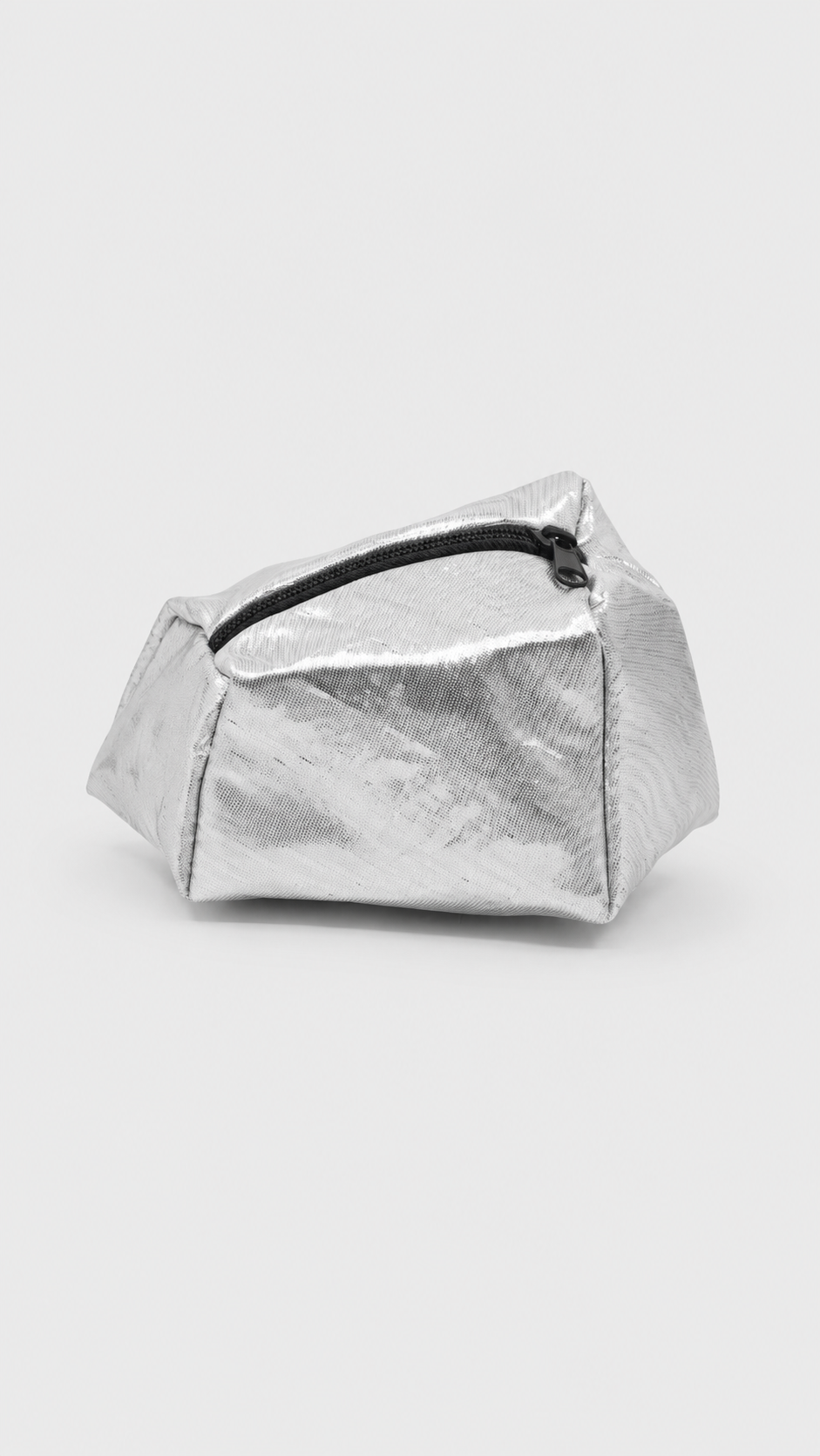 Sac à cosmétiques ou trousse de toilette argenté avec fermeture éclair noire, posé sur une surface blanche.