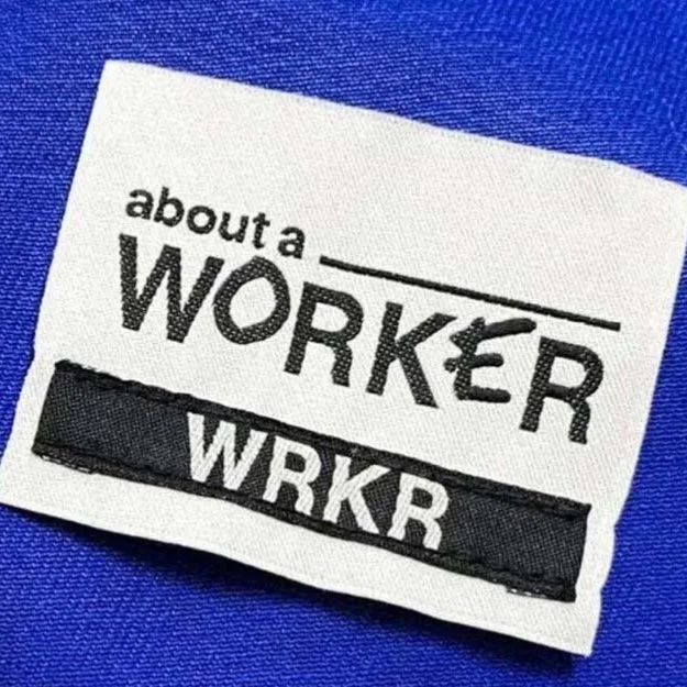 Étiquette de vêtement avec le texte 'about a WORKER' et 'WRKR' sur un fond bleu.