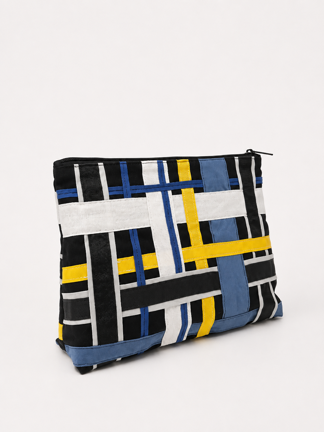 Sac en tissu à motifs géométriques avec des bandes de couleurs bleu, blanc, jaune, noir et gris, avec une fermeture éclair en haut.