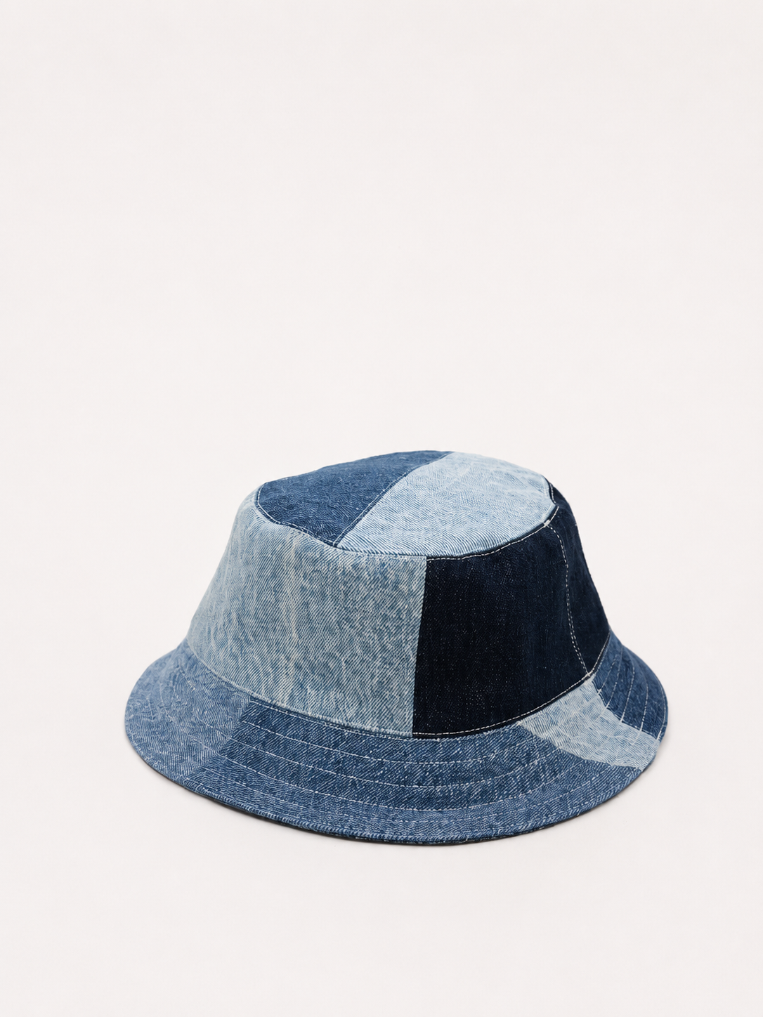 Chapeau bucket en denim avec motifs patchwork en différentes nuances de bleu.