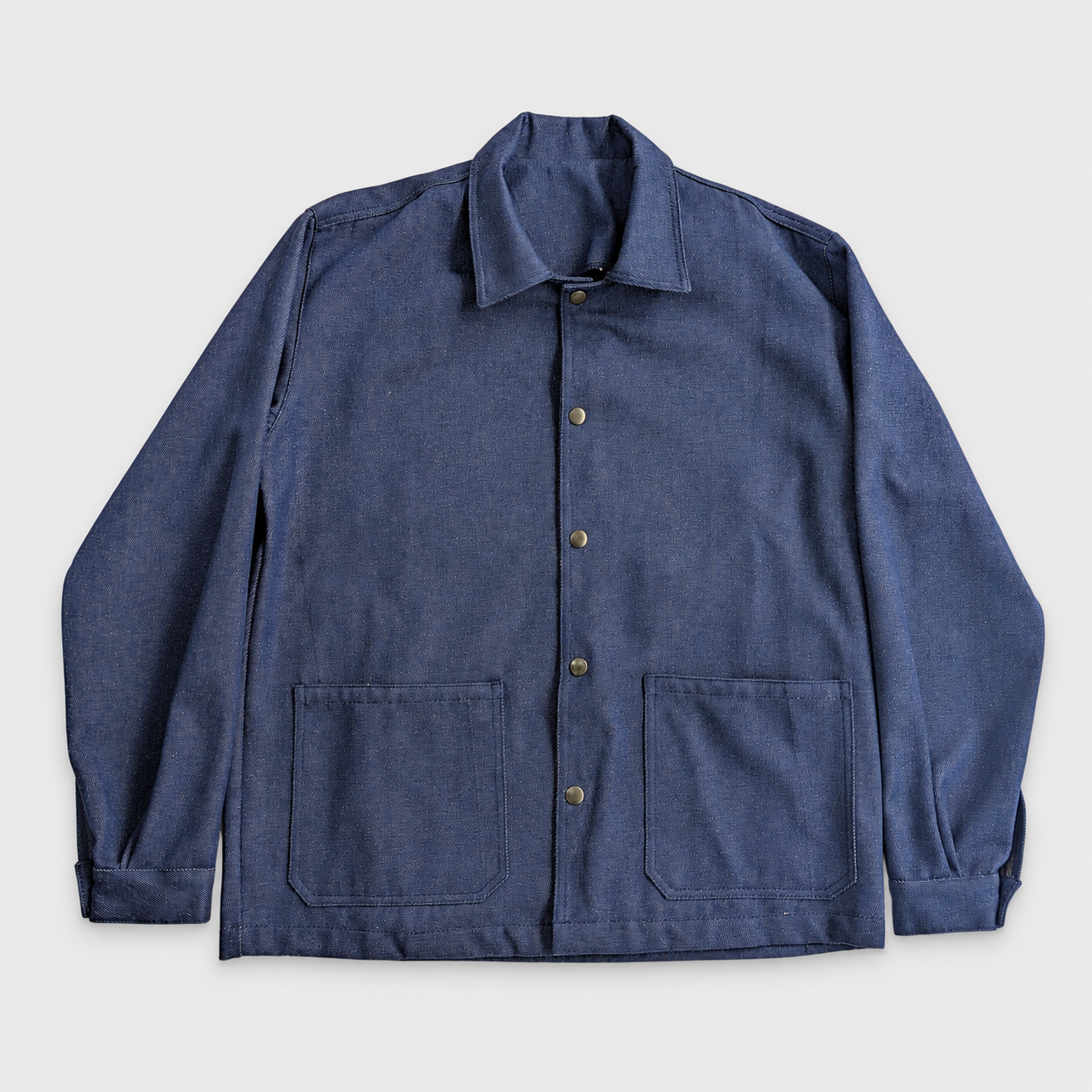 Veste en denim bleue avec boutons pression et deux poches devant.