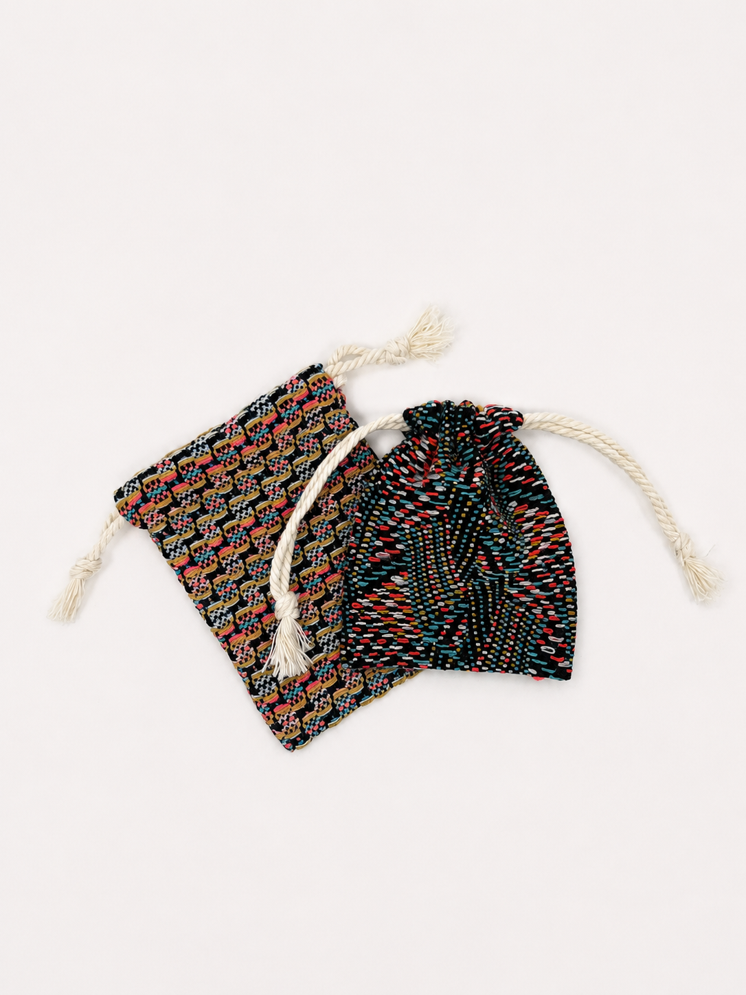 Deux petits sacs en tissu avec des cordons de serrage, l'un à motifs géométriques colorés, l'autre à motifs de points multicolores.