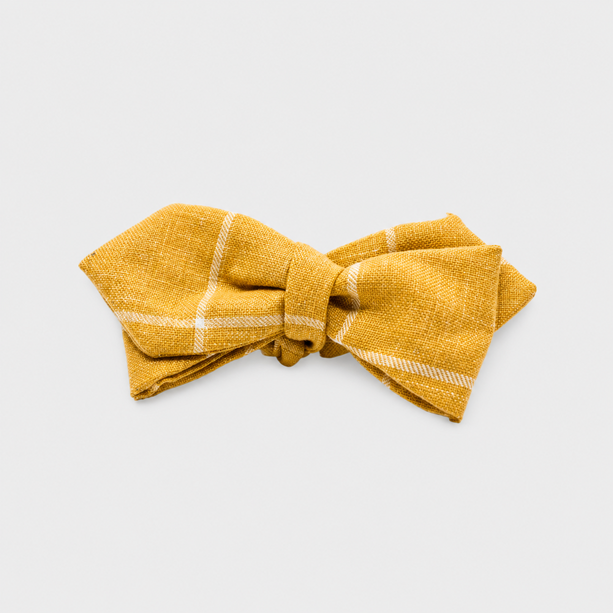 Un nœud papillon en tissu jaune avec des lignes blanches sur fond blanc