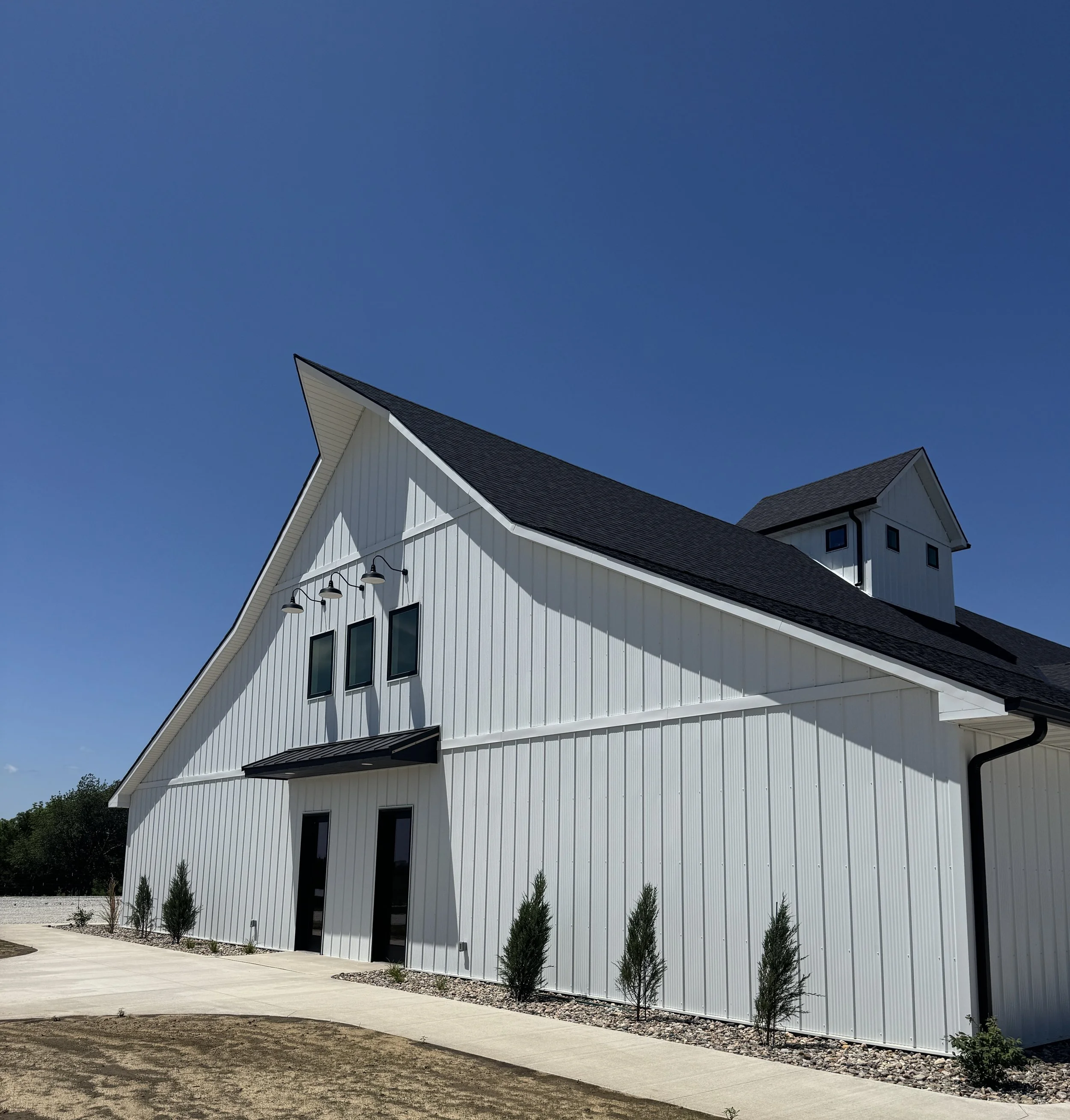 A modern white wedding barn style building with a black barn roof and fully landscaped for any luxury wedding in the Des Moines Area