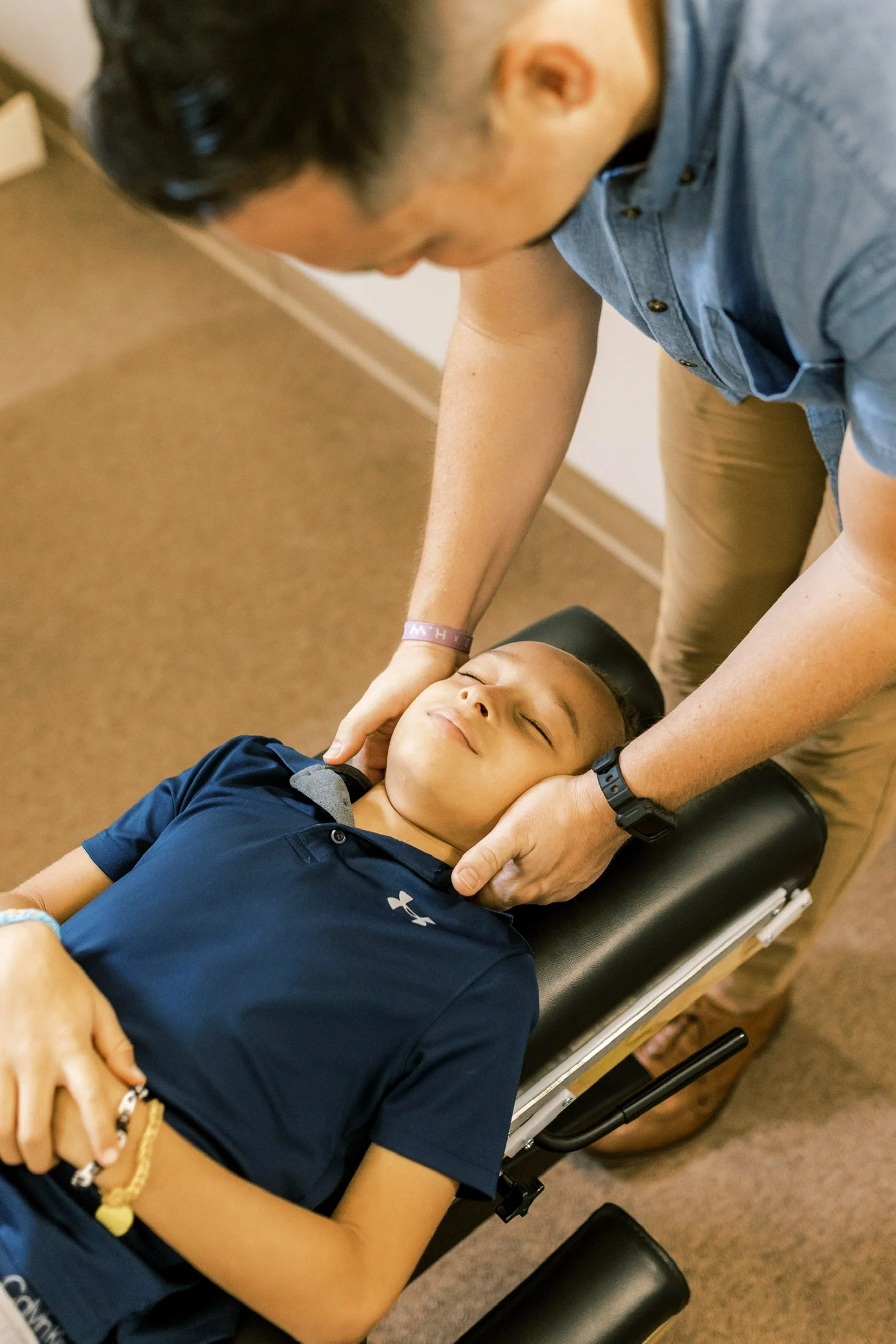 Chiropractor adjusting child's neck on therapy table