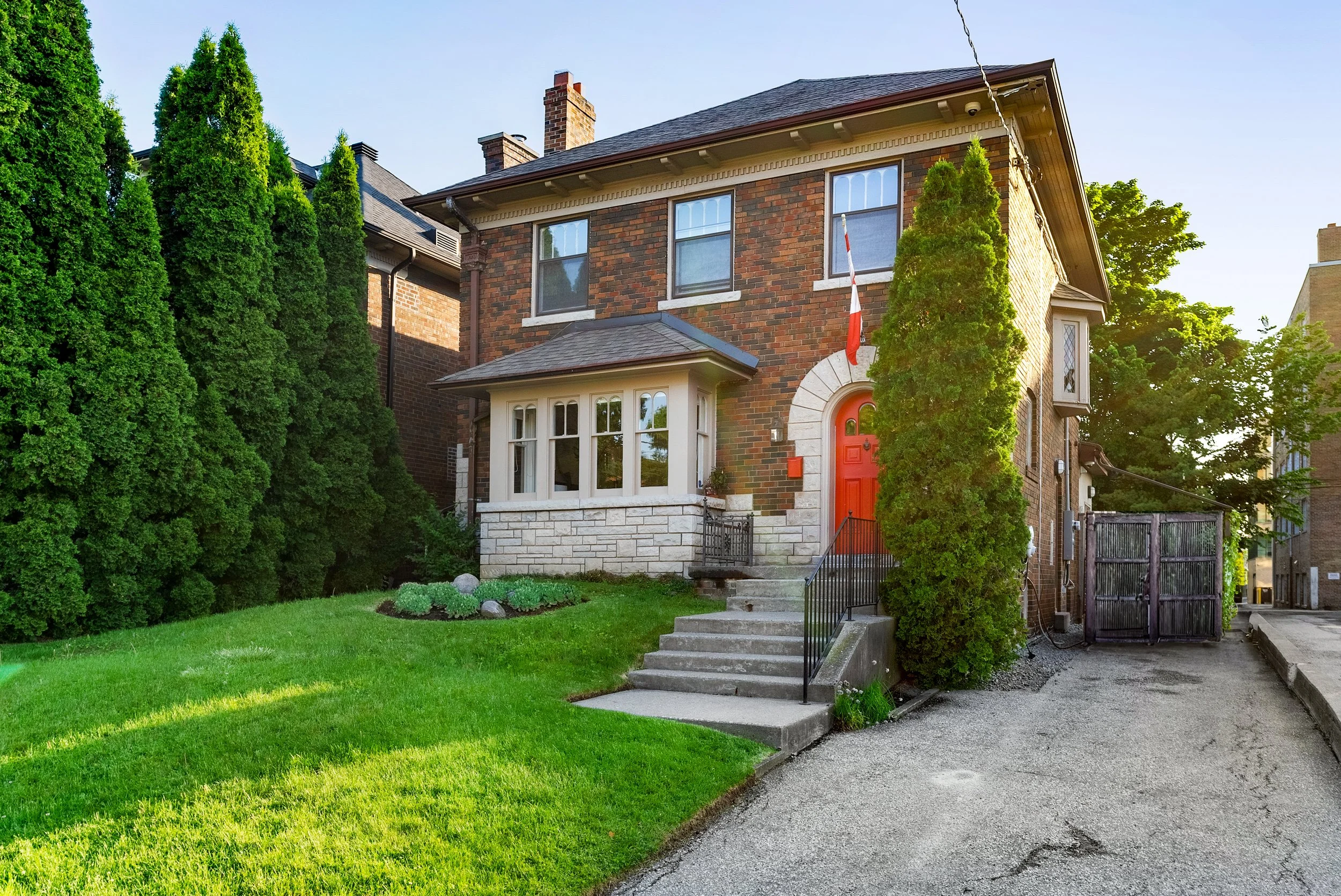 Curbside view of a brick home with a bright red door