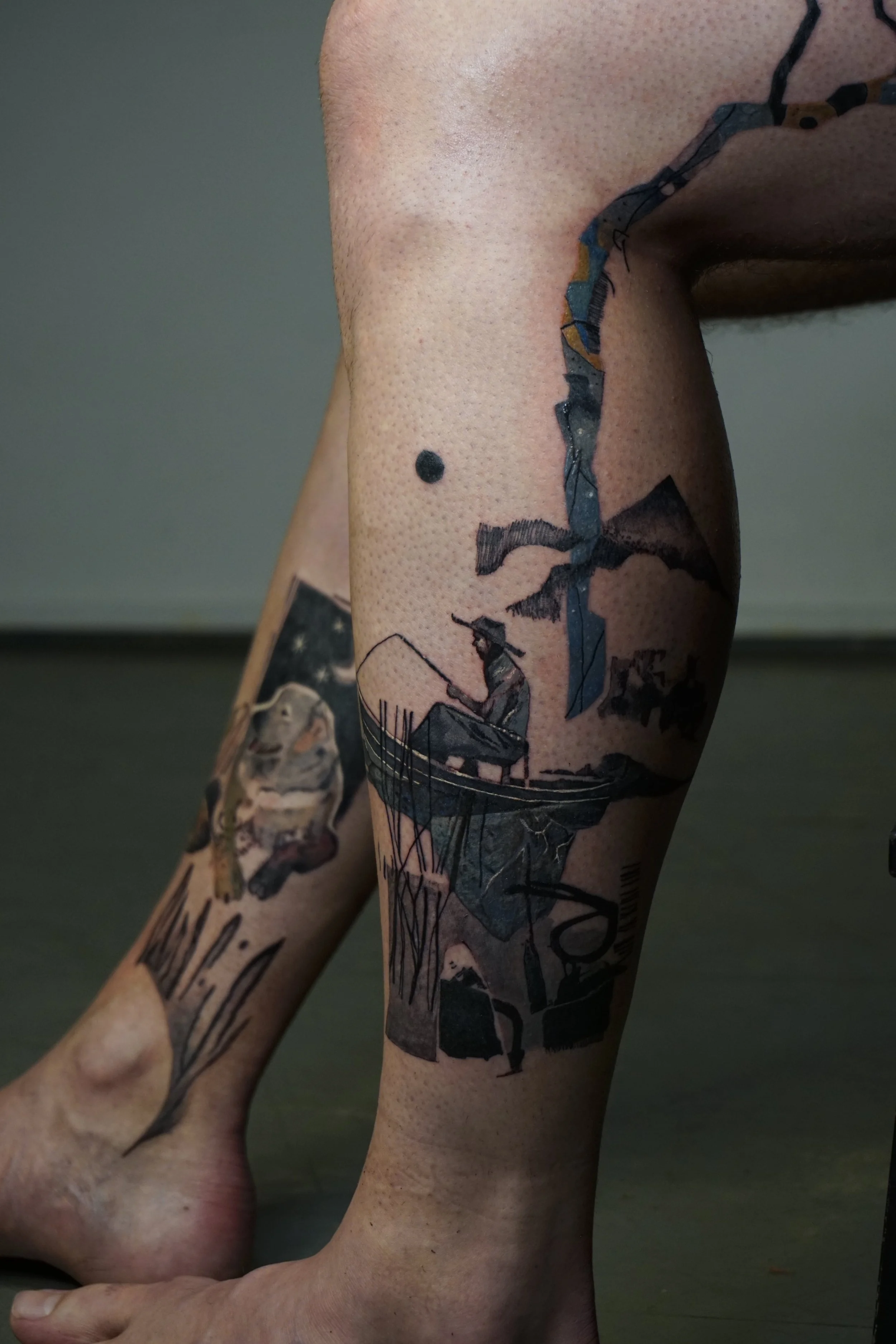 Tattoo of a man fishing on a boat, with mountains and a bird in the sky, on a person's calf.
