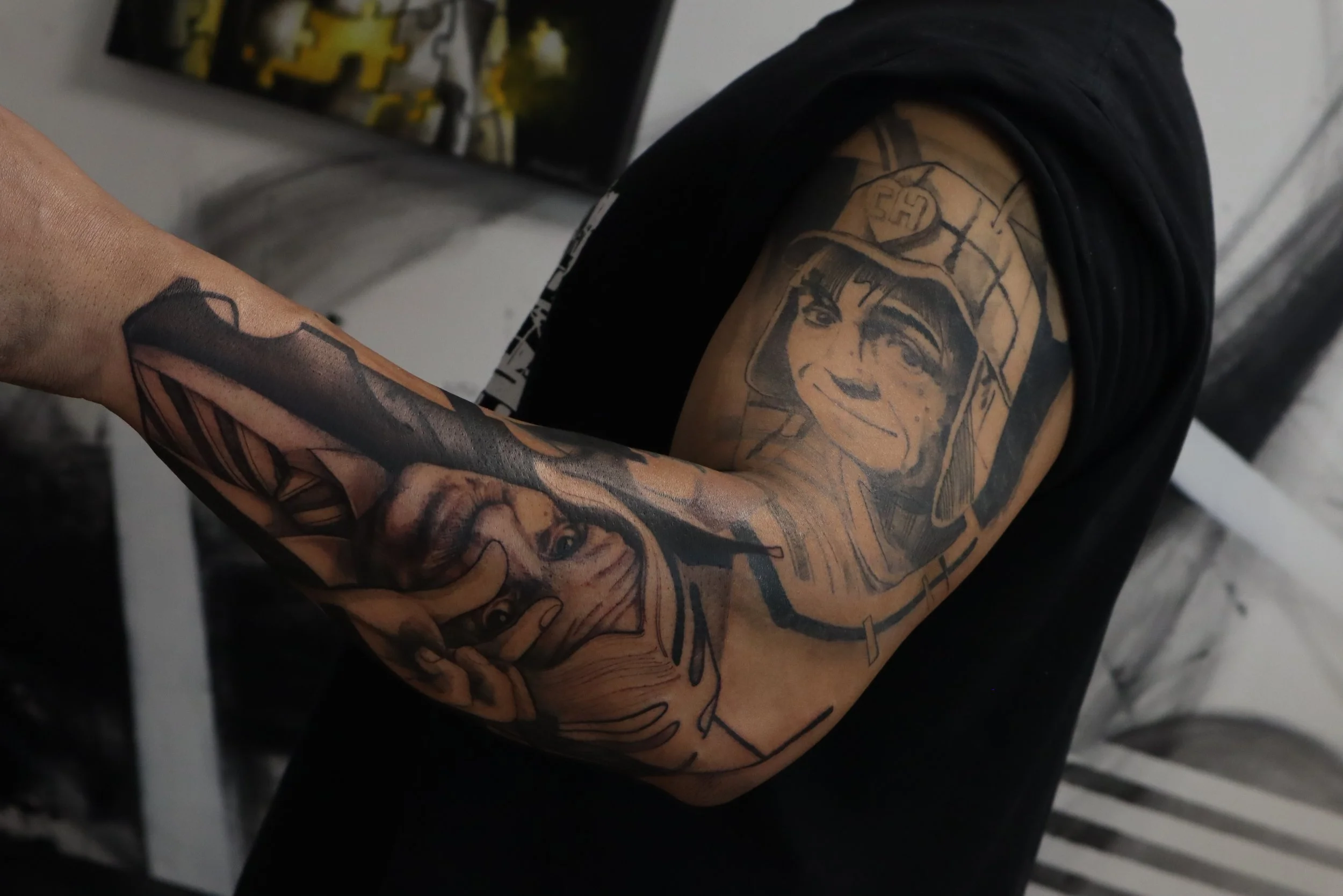 Arm tattoo of a soldier and a portrait on a person's bicep.
