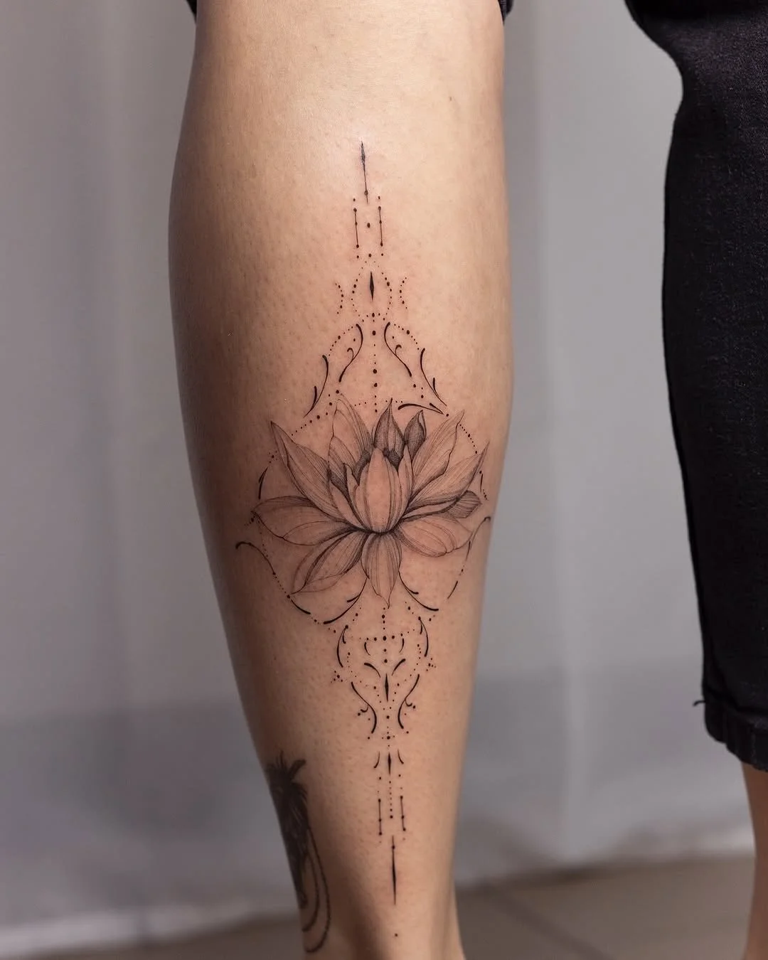 A tattoo of a lotus flower with intricate line details on a person's thigh.