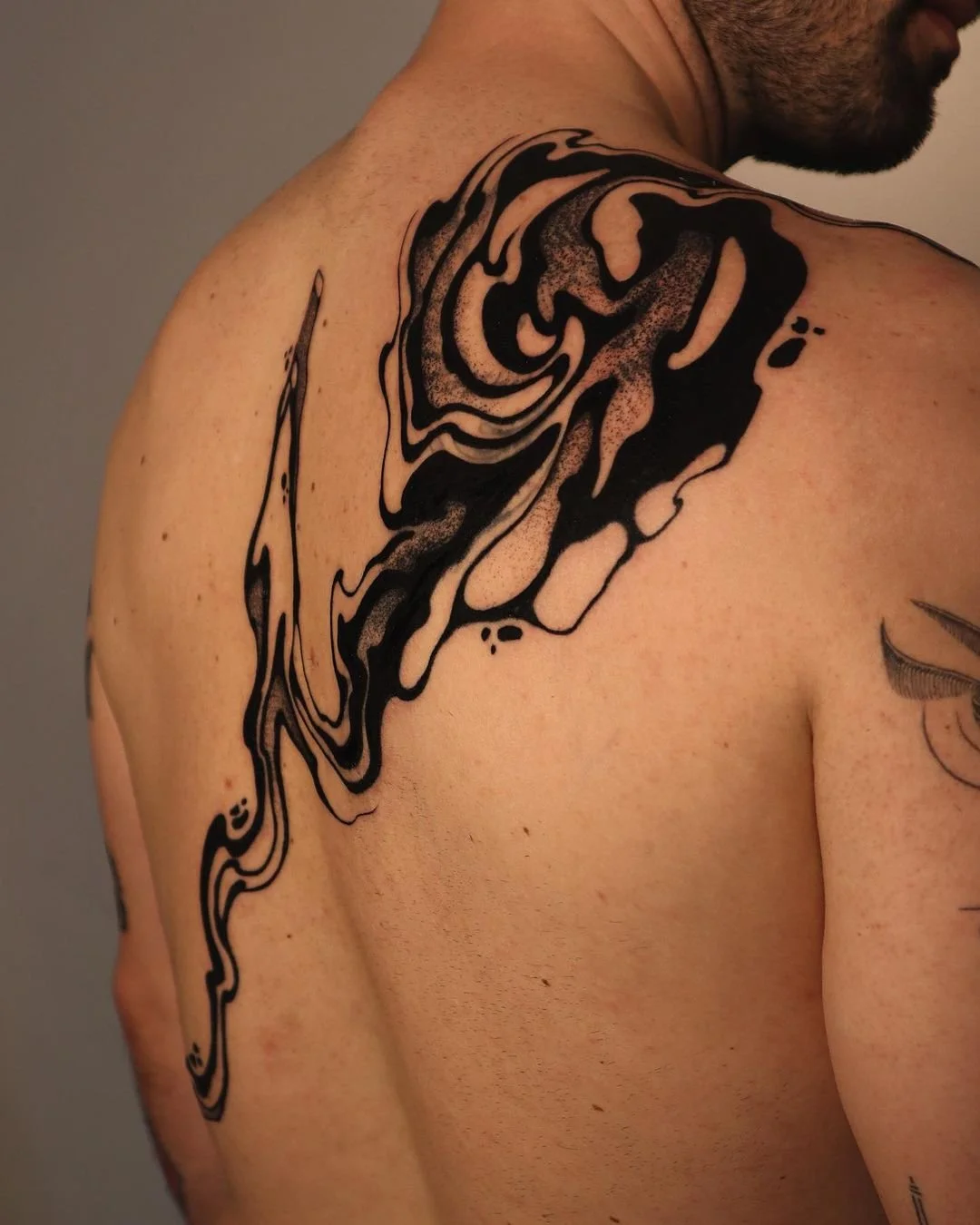 Abstract black ink tattoo design on man's upper back.