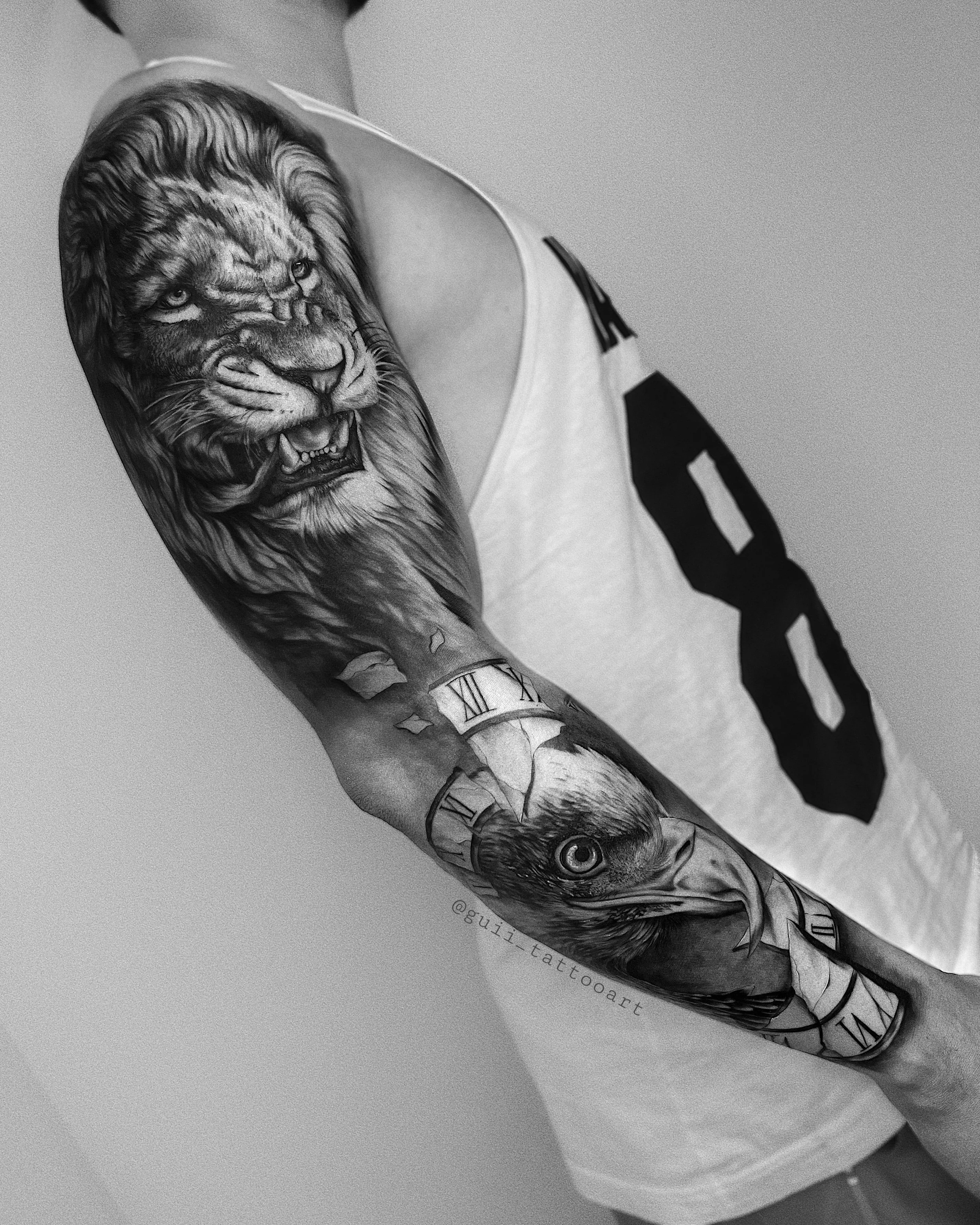 Black and gray tattoo sleeve featuring a lion and an eagle, with Roman numerals wrapped around the arm.