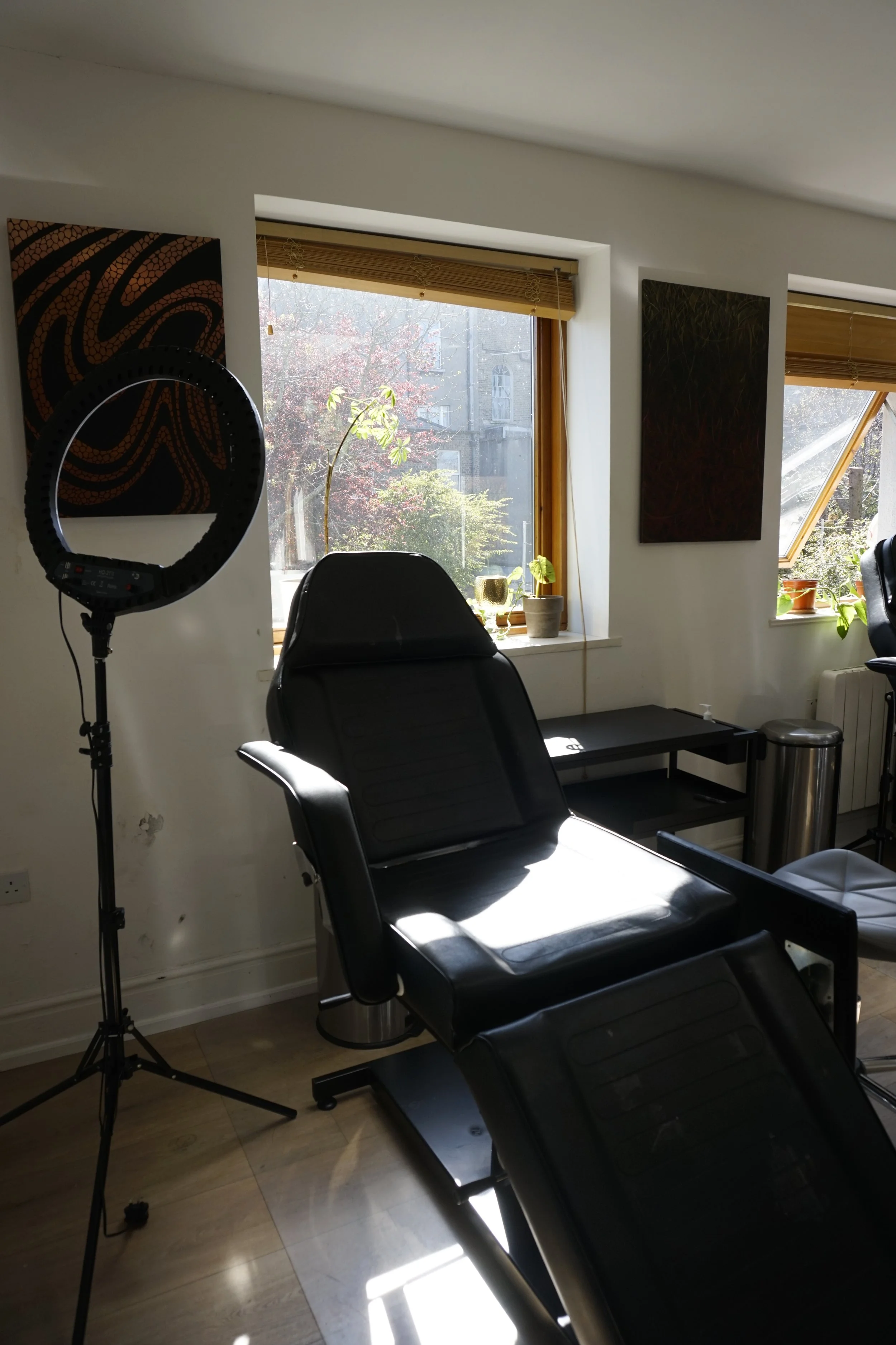 Tattoo studio with chair, ring light, and artwork on walls
