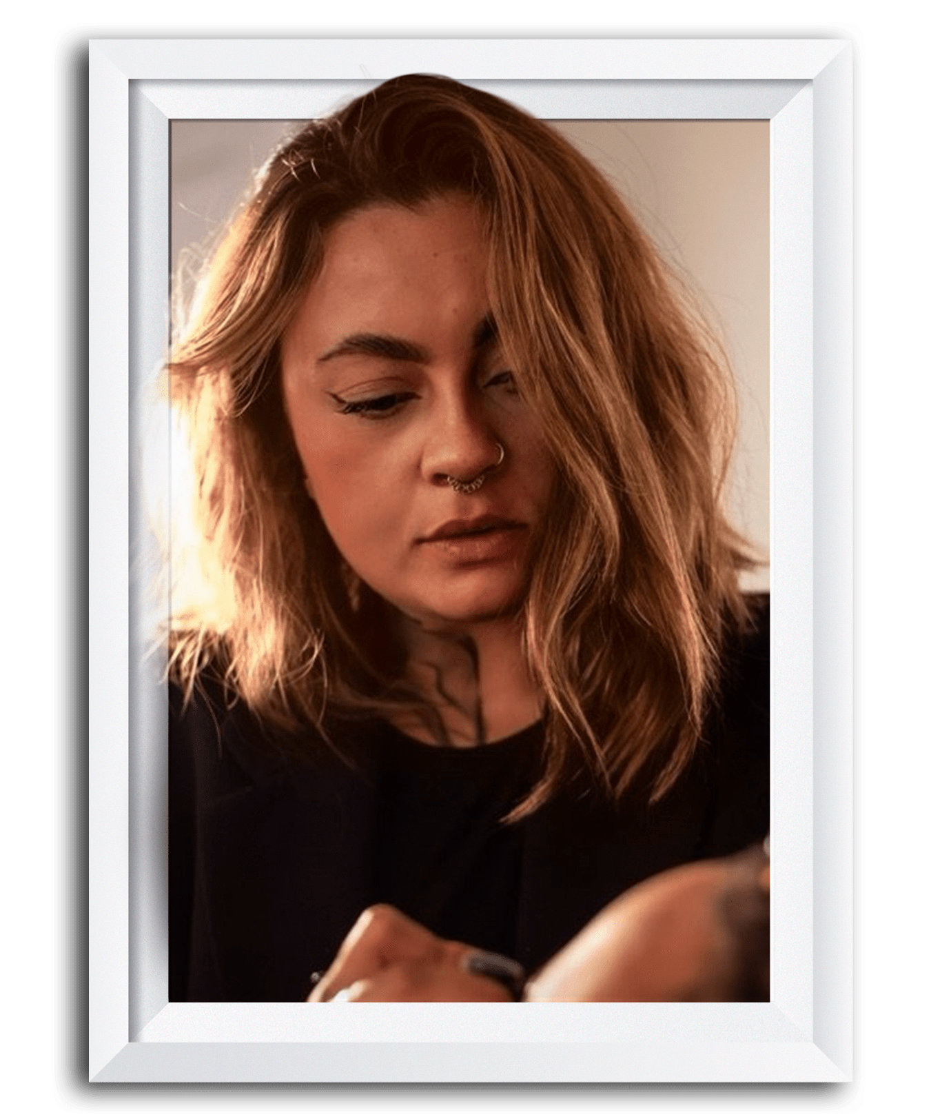 A woman with shoulder-length wavy red hair, winged eyeliner, nose ring, and a septum piercing looking at her phone.