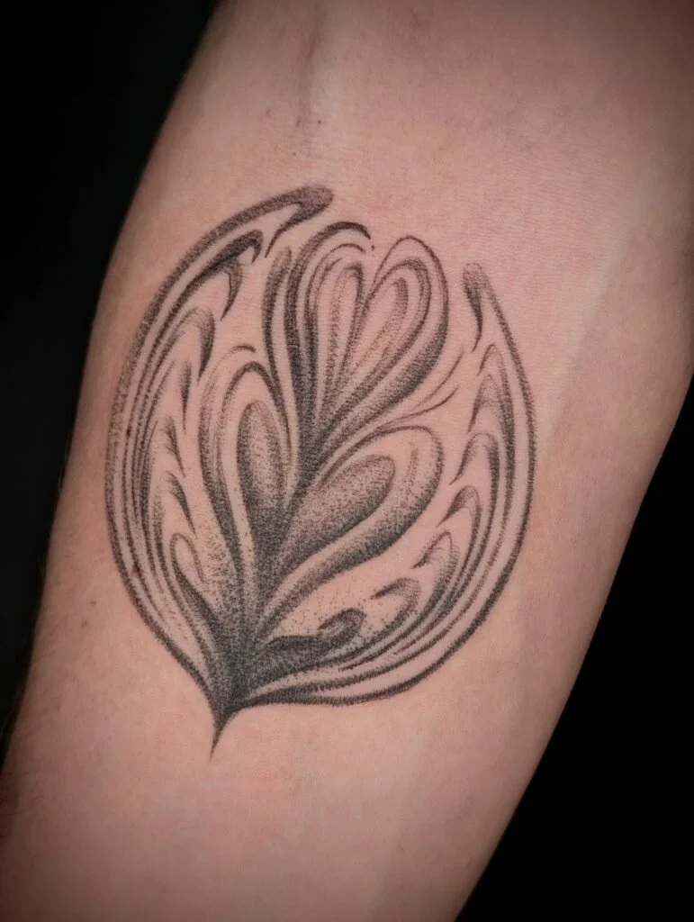 Black and gray tattoo of a stylized, abstract lotus flower on skin.