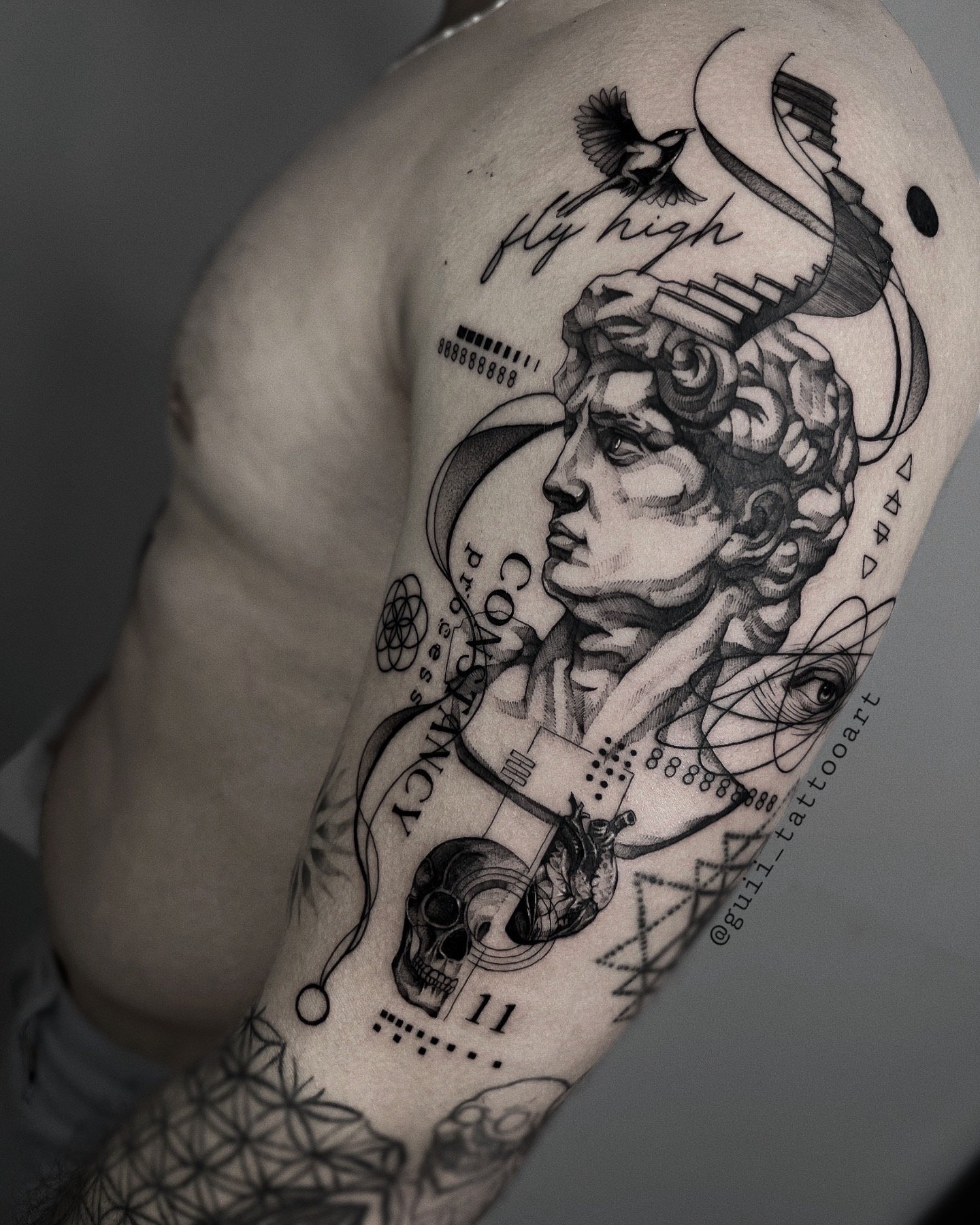 Tattoo sleeve with Greek statue, skull, heart, geometric patterns, and 'fly high' text.