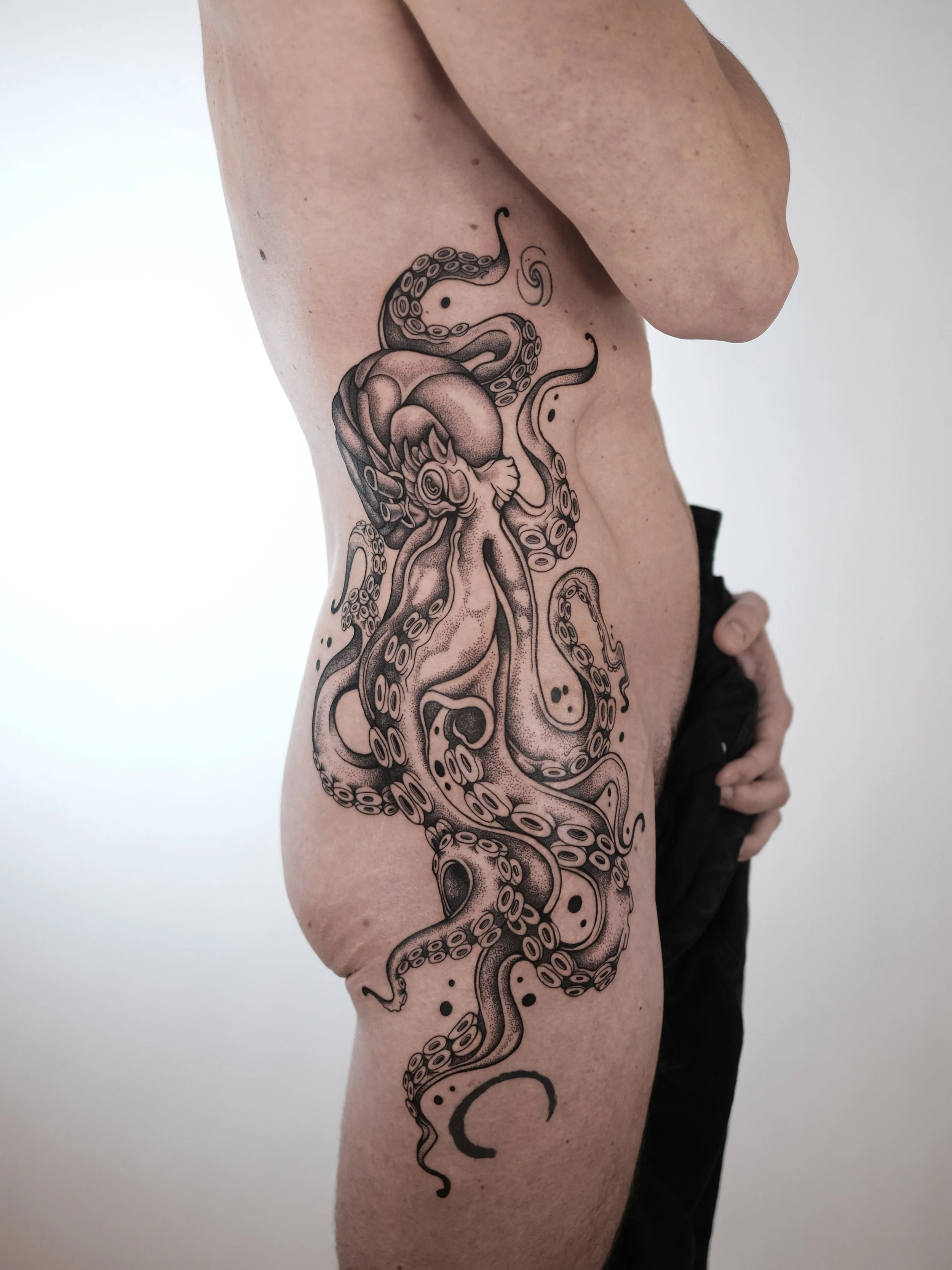 A person with a large tattoo of an octopus on their upper thigh and hip