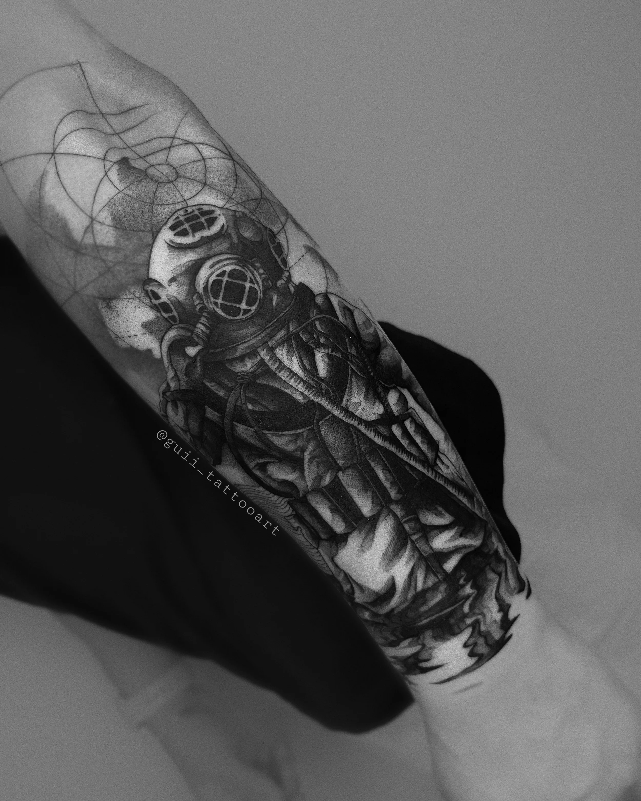 Black and white tattoo of a deep-sea diver helmet on forearm