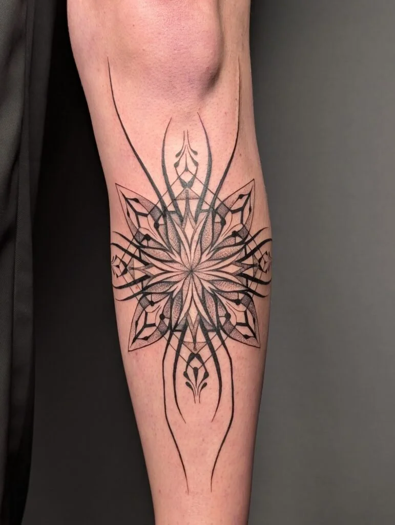 Geometric tattoo design on arm featuring symmetrical lines and shapes in black ink.