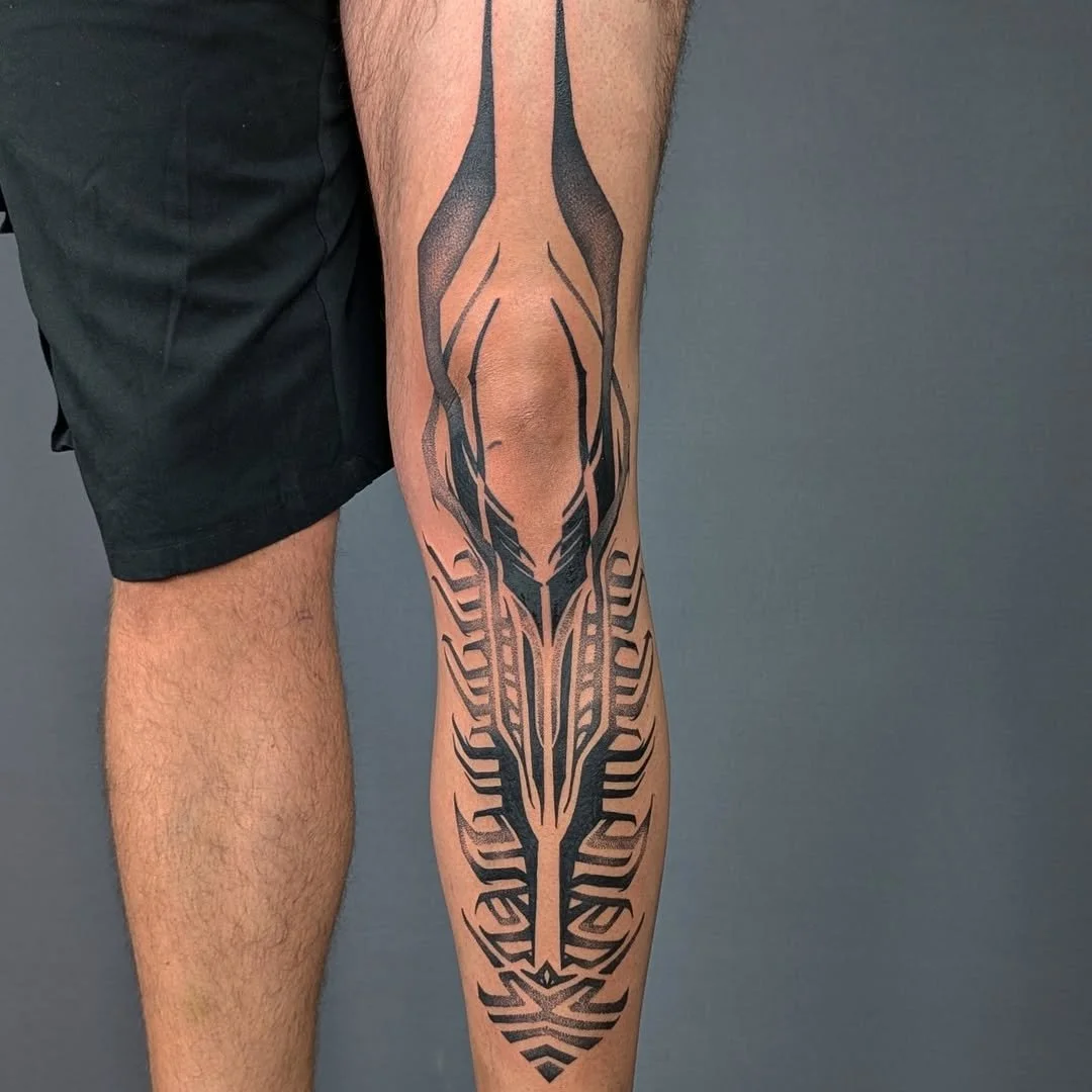 A tattoo of a tribal-style design running down a person's calf.