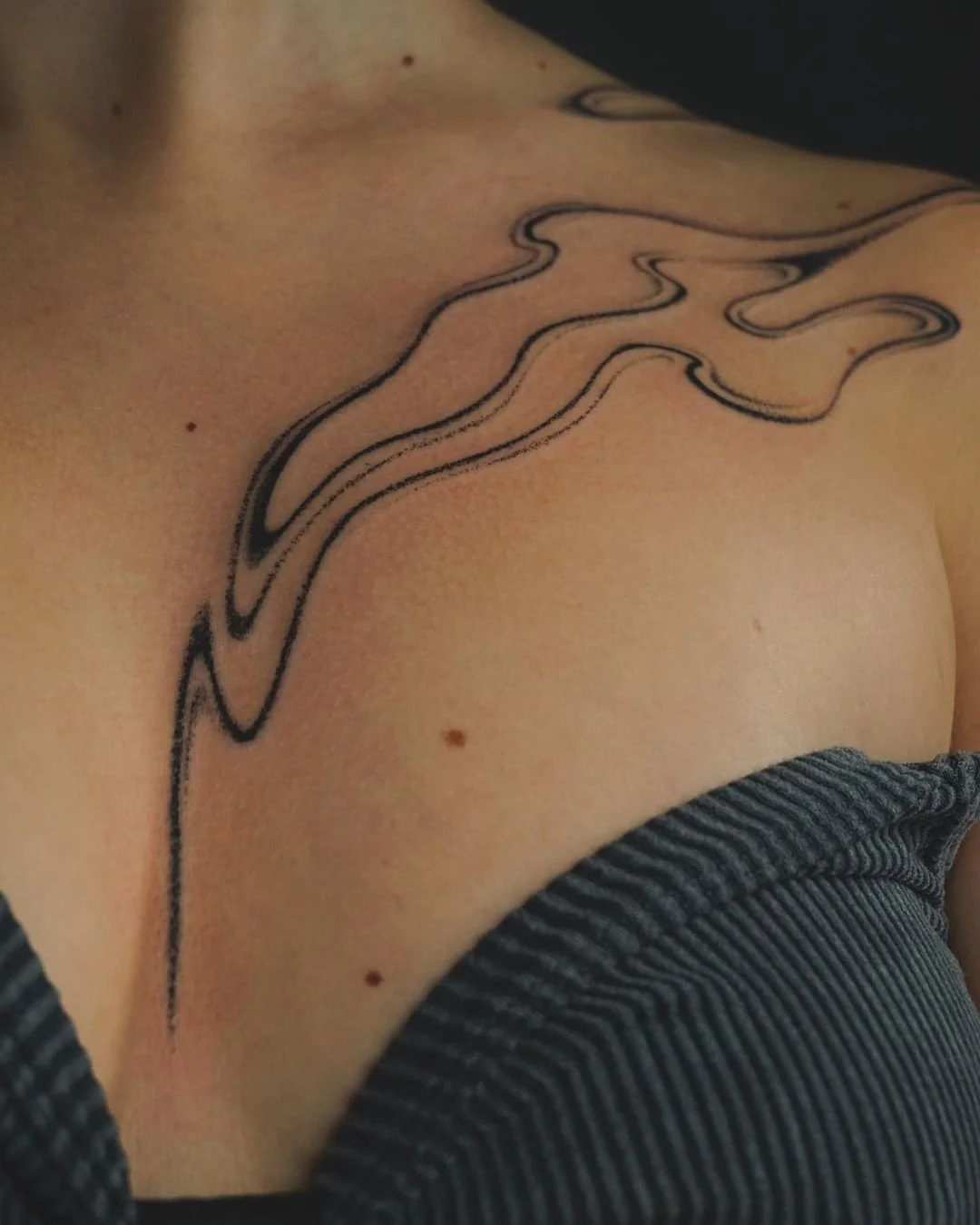 Abstract black line tattoo on person's shoulder and chest