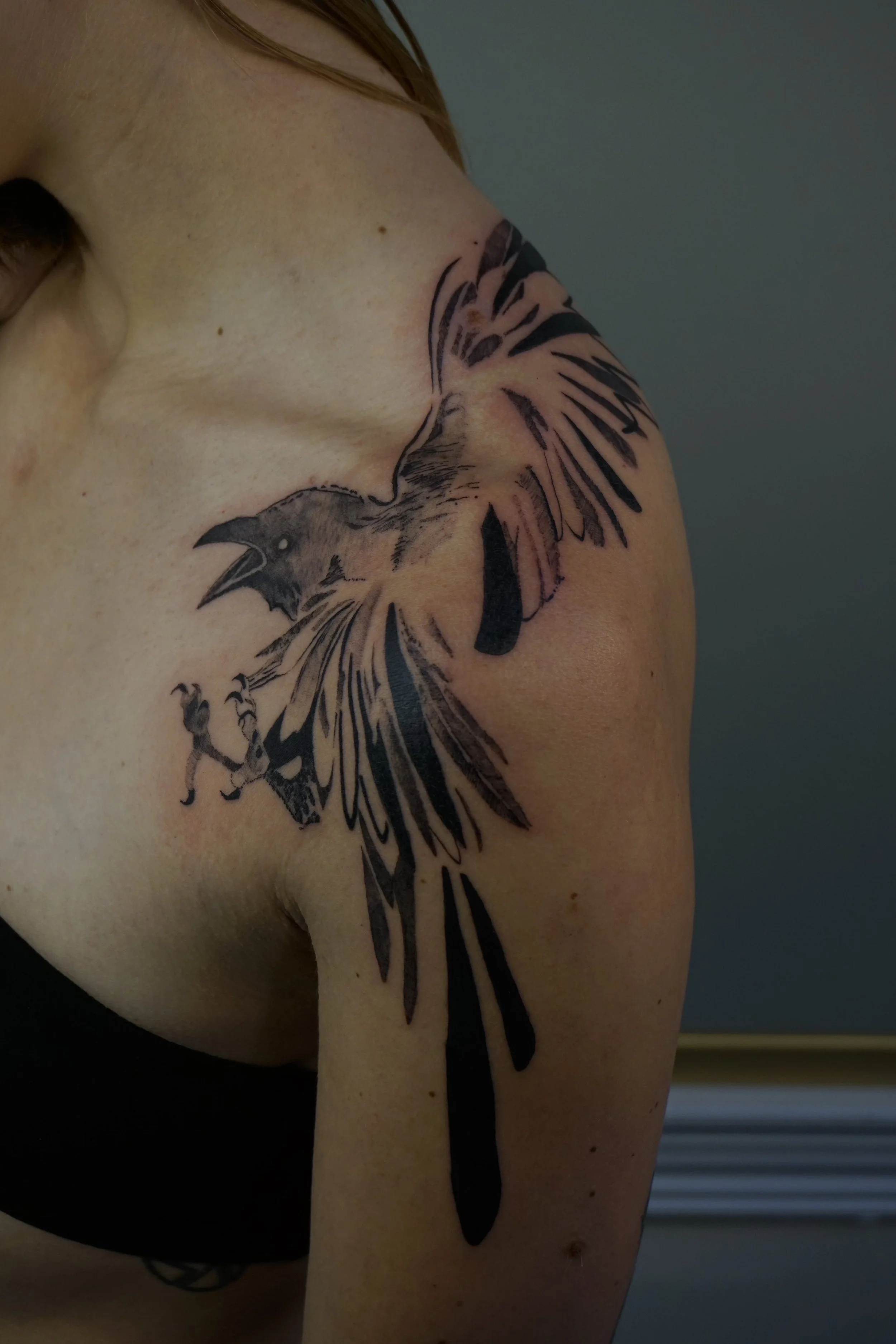 Tattoo of a roaring eagle or hawk with outstretched wings on person's shoulder and upper arm.