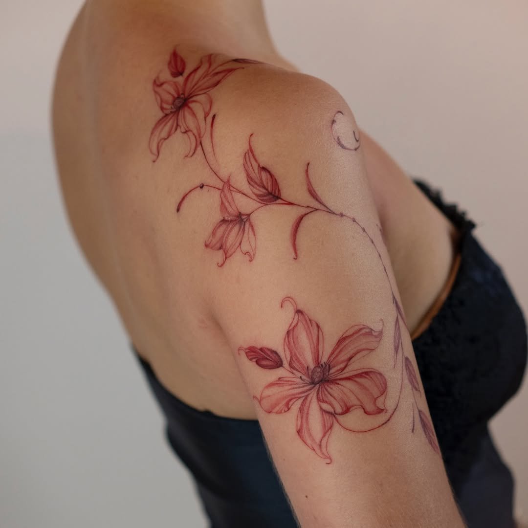 Tattoo of pink lilies on a person's upper arm and shoulder.