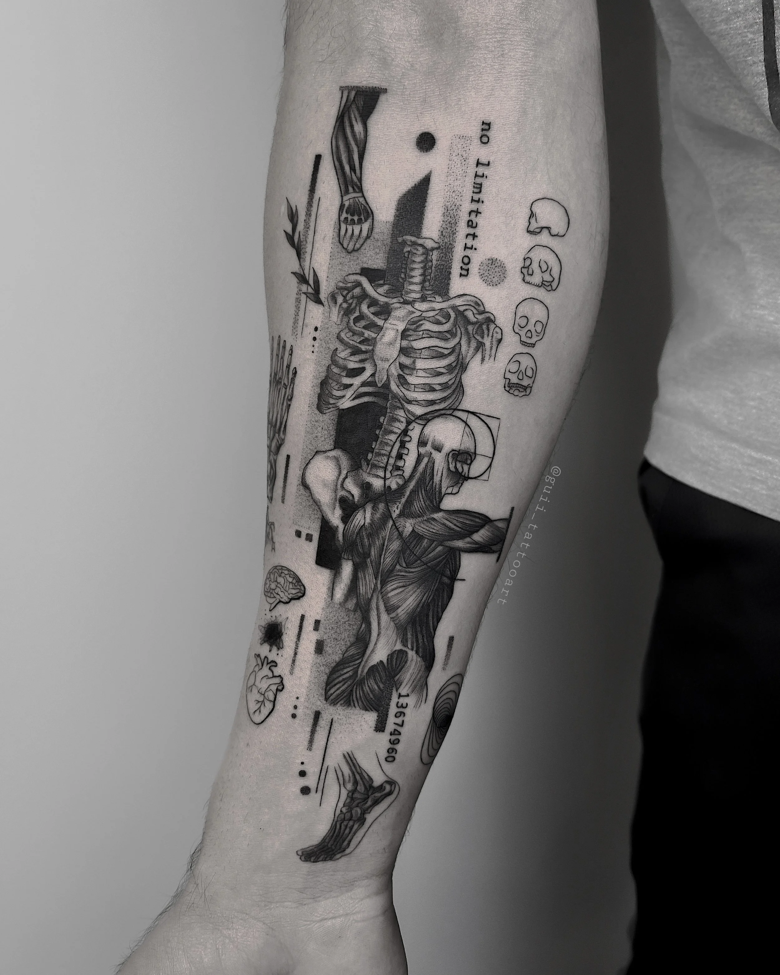 Forearm tattoo featuring anatomical elements, skeleton, muscles, brain, heart, smaller skulls, text "no limitation," and abstract geometrical designs.