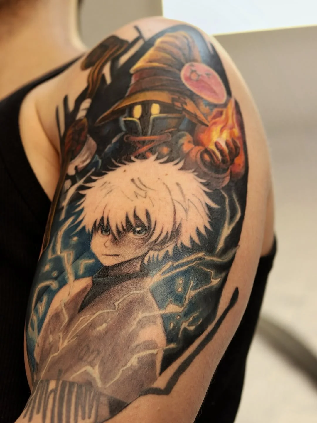 Tattoo of a young anime character with white hair, along with a wizard wearing a hat, and a creature with glowing yellow eyes holding a flame on the shoulder.