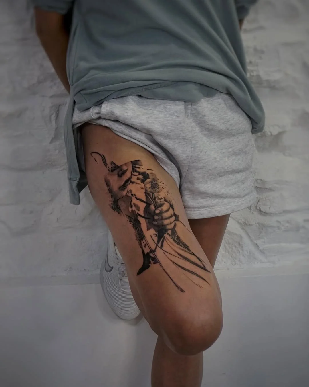 Tattoo of a person holding a bow and arrow on a person's thigh, with a detailed face and bow illustration.