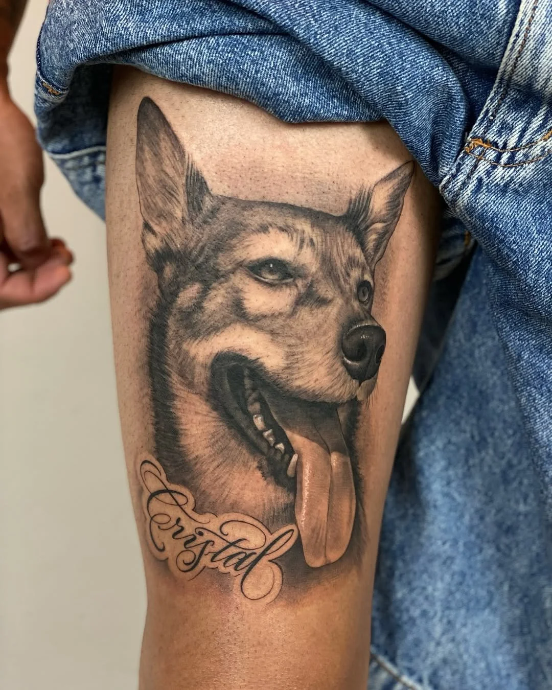 Tattoo of a happy, realistic Husky dog with its tongue out, located on a person's upper thigh, with the word 'Perstad' written in cursive below the dog's face.