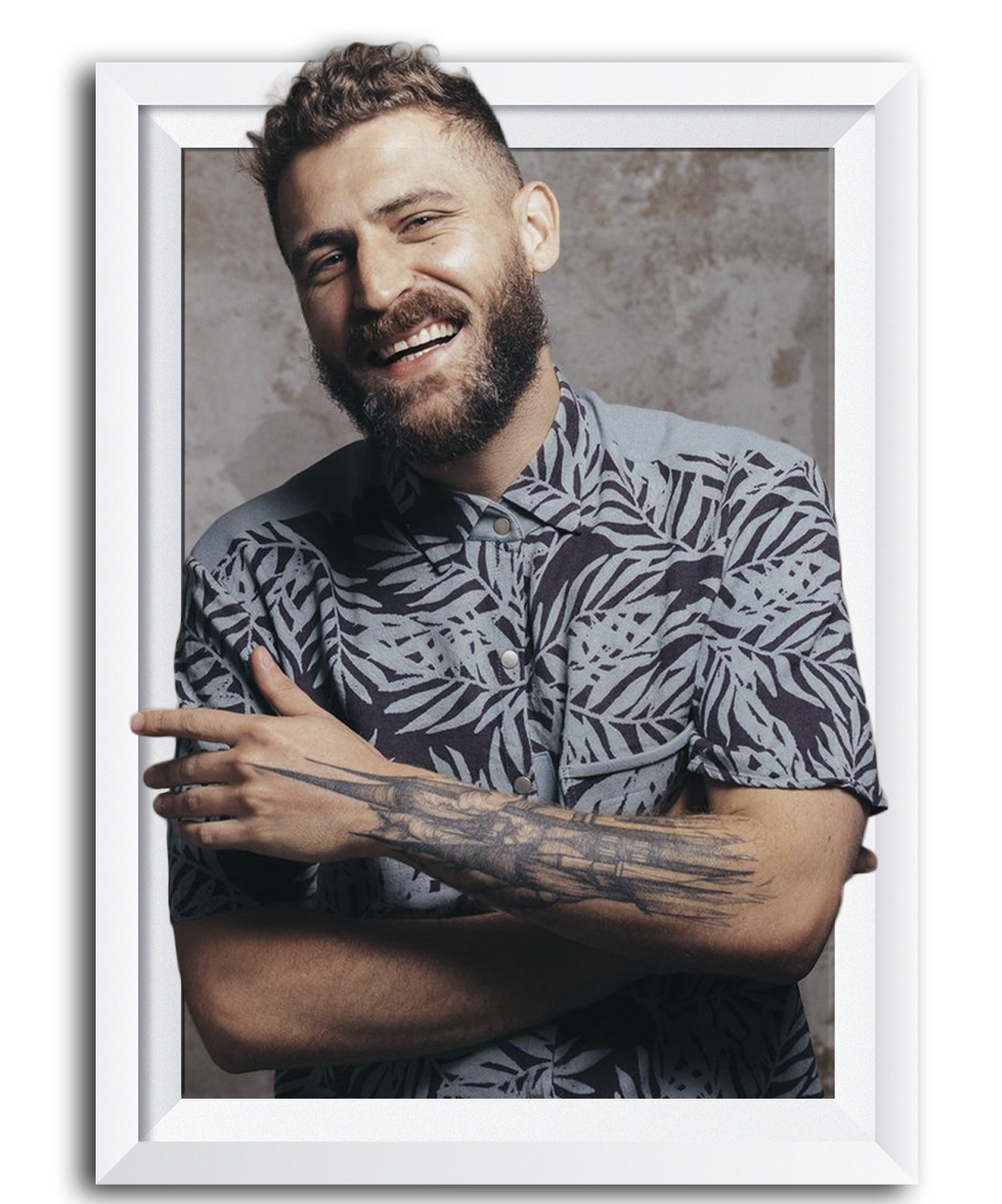 Smiling man with tattoos wearing a patterned shirt, framed photo