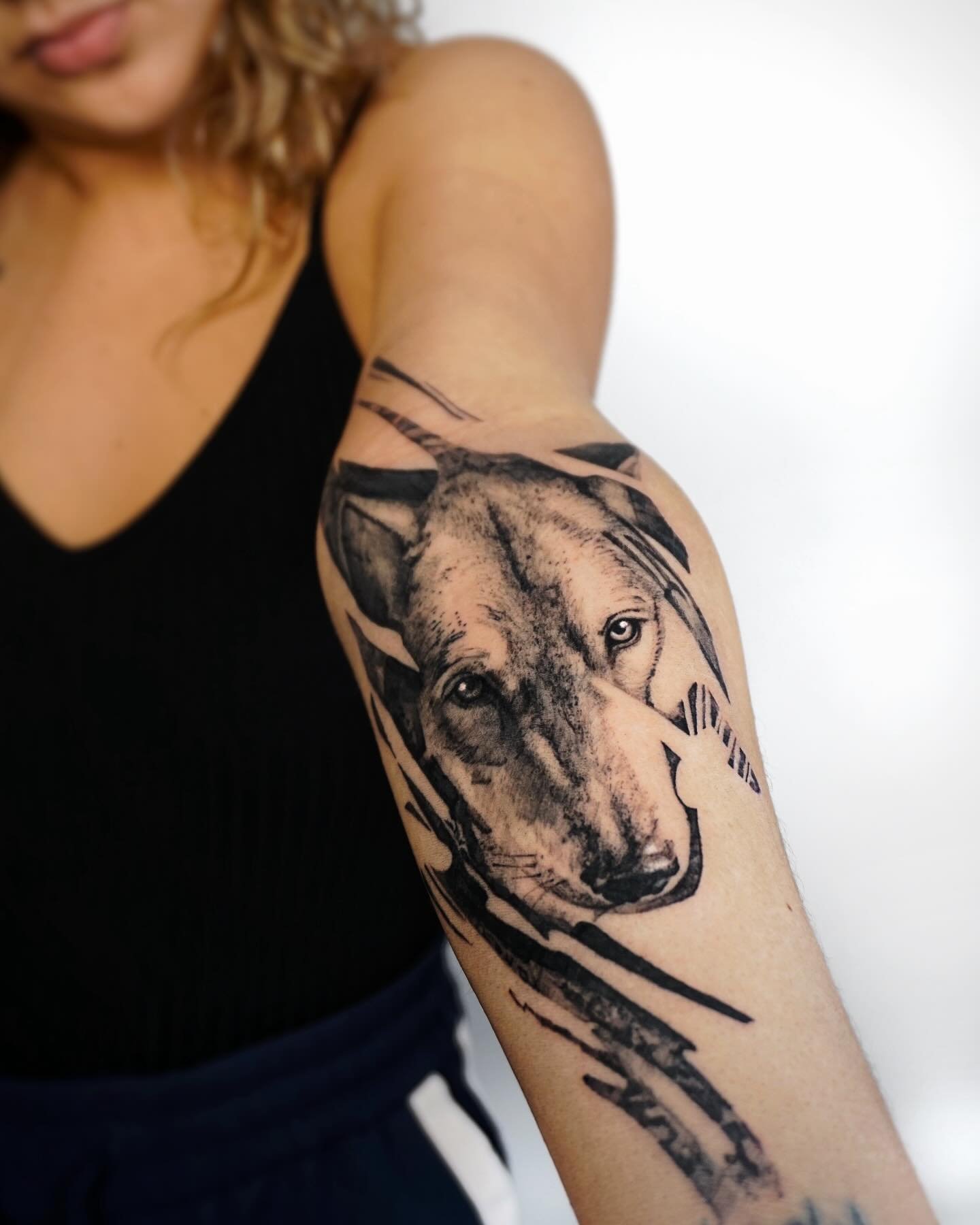 Black and grey tattoo of a wolf's face on the person's upper arm.