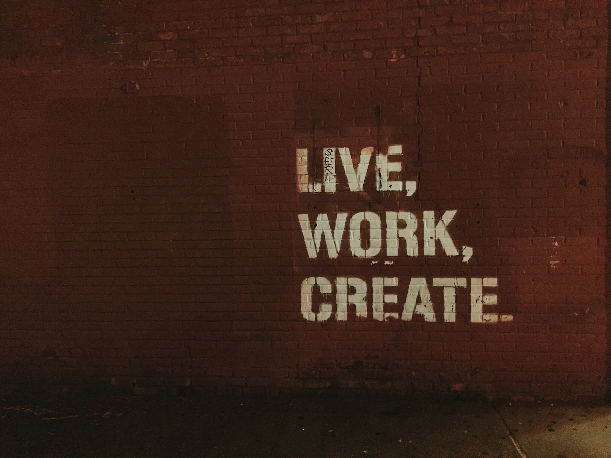 Brick wall with graffiti saying "Live, Work, Create."