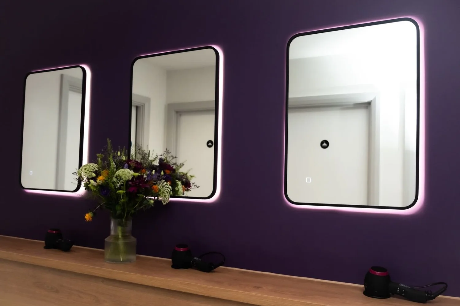 Backlit LED mirrors on a dark feature wall in a studio changing area, Leicester