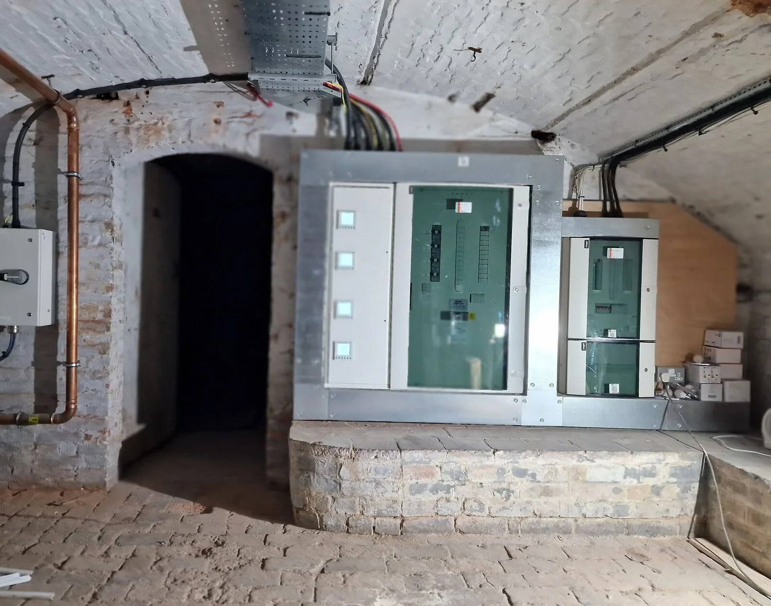 New distribution boards with steel surrounds and cable tray in a vaulted brick cellar plant room, Leicester