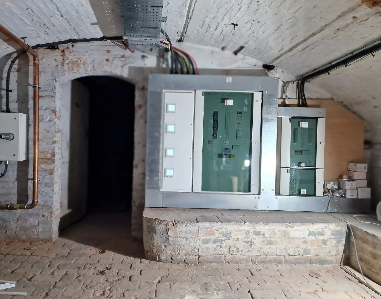 New distribution boards with steel surrounds and cable tray in a vaulted brick cellar plant room, Leicester