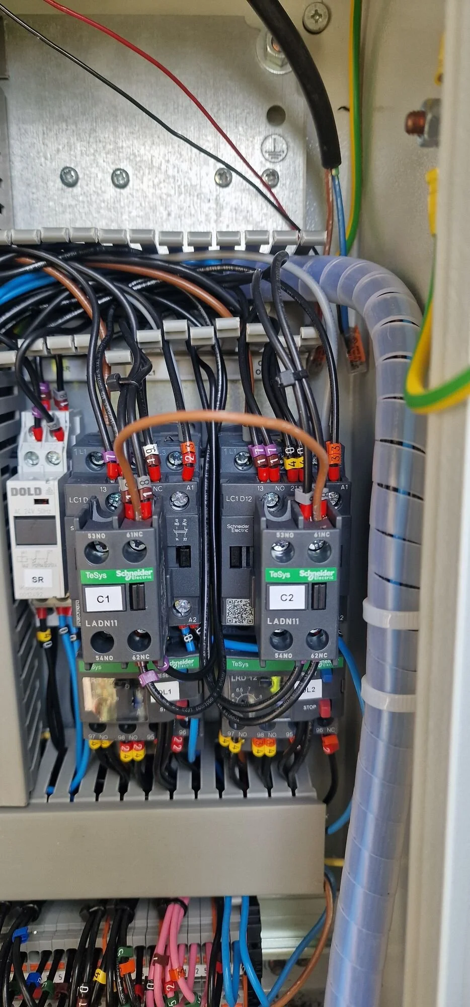 Inside a pump control panel showing contactors and control wiring during repair work