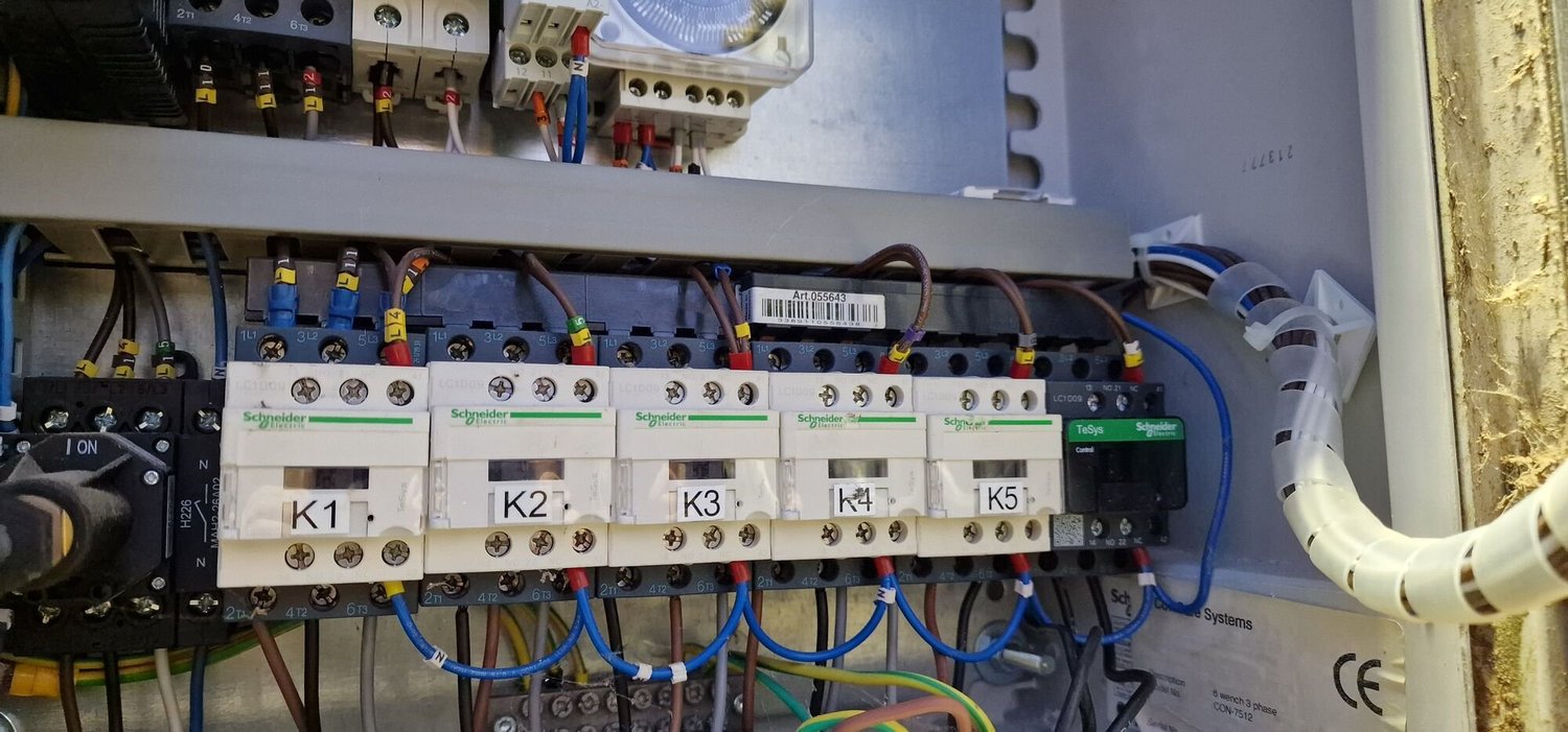 Inside a farm control panel showing a row of contactors after repair work