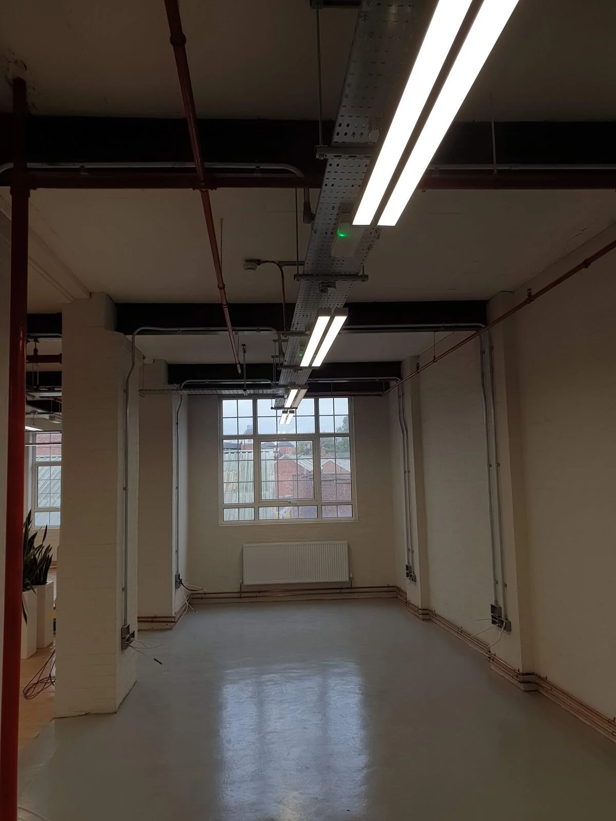 Steel cable tray run alongside linear LED lighting in an office corridor