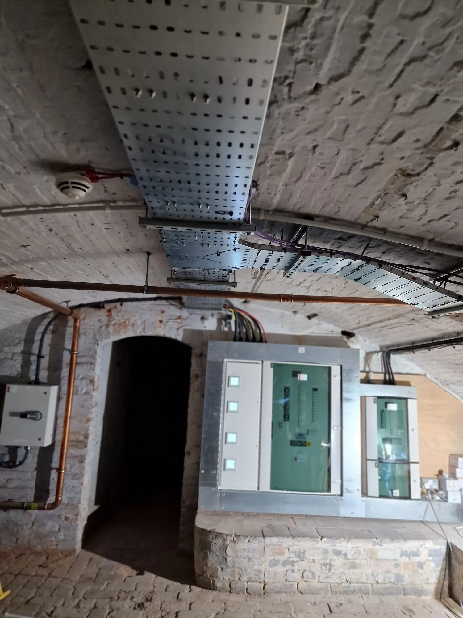 Perforated steel cable tray carrying sub-main cables to new distribution boards in a vaulted cellar plant room, Leicester