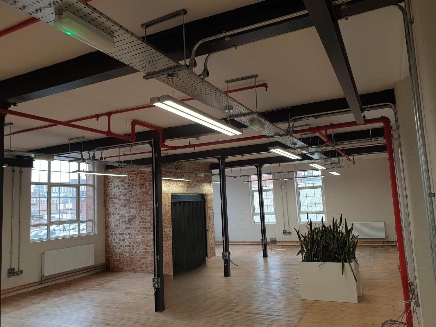 Office with steel cable tray and LED lighting at high level, sockets and a floor box in a timber floor