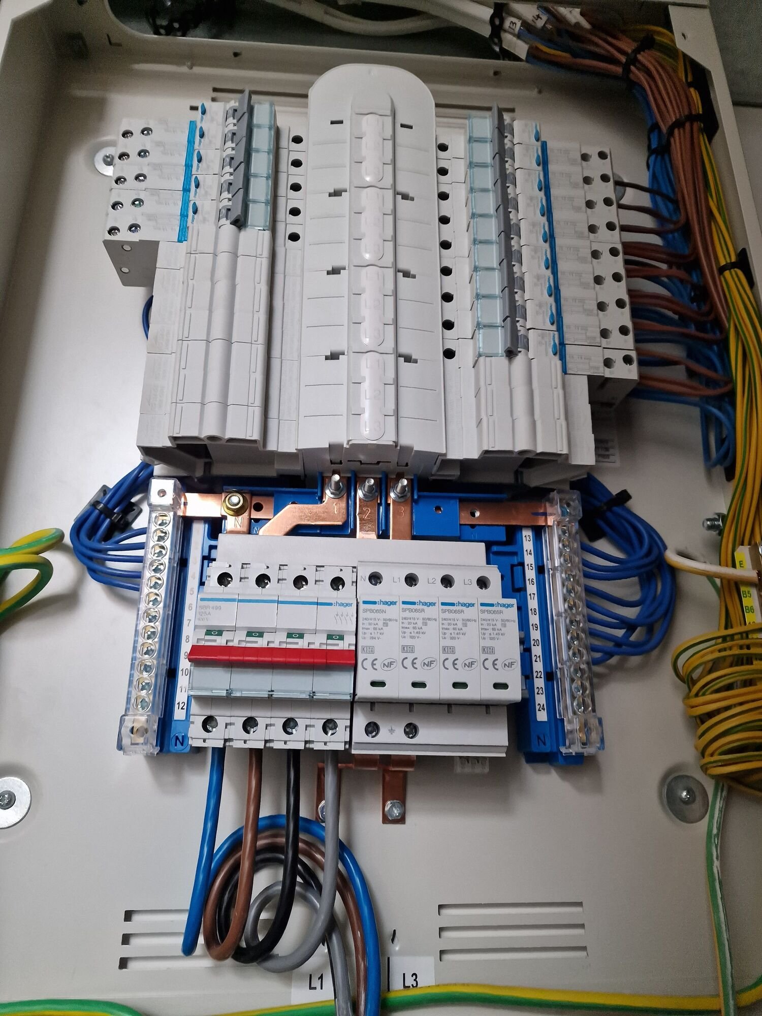 Inside a three-phase distribution board during installation, showing neat wiring and busbar