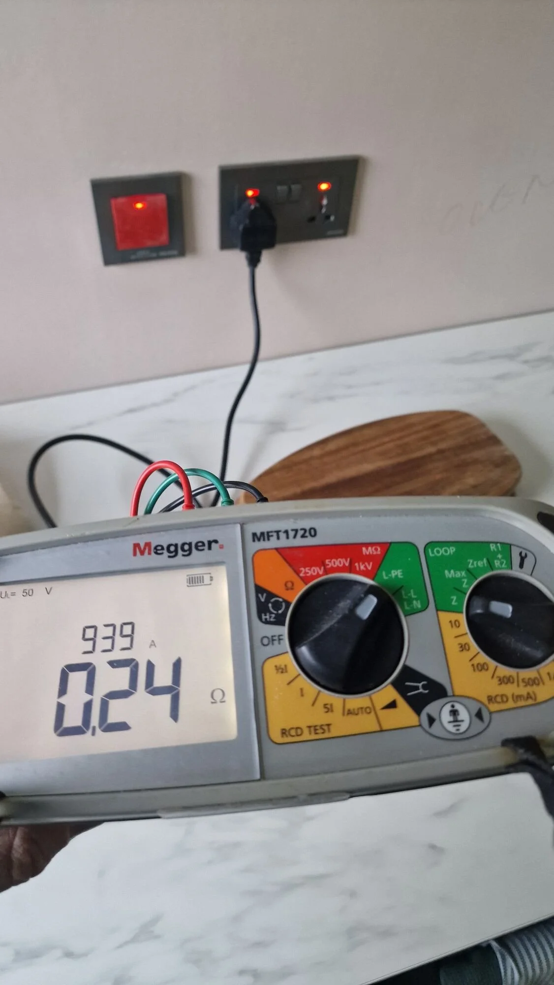 Calibrated multifunction tester plugged into a socket outlet, taking readings during testing