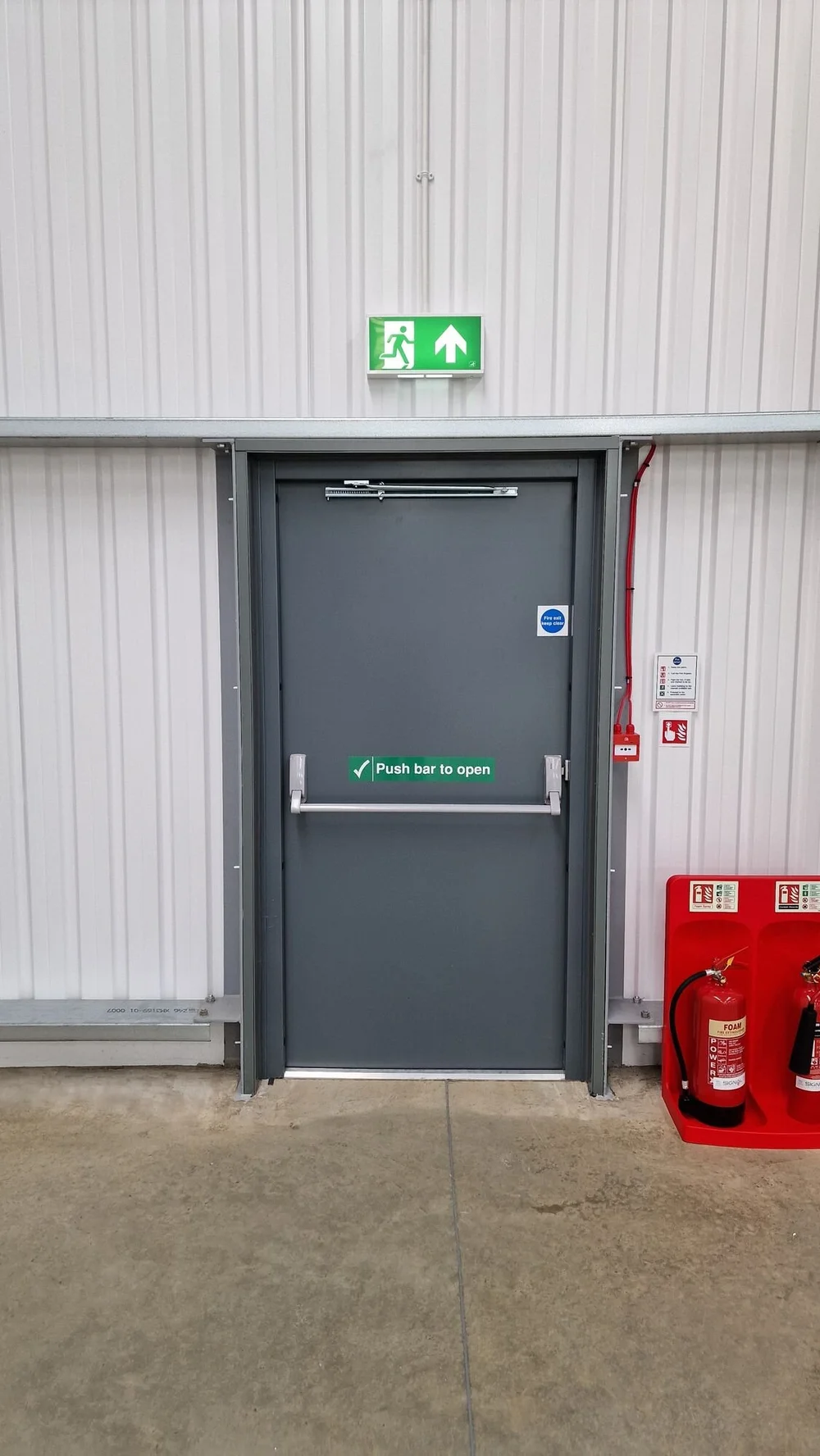 Emergency lighting exit sign above a fire exit door in a commercial unit, Kibworth