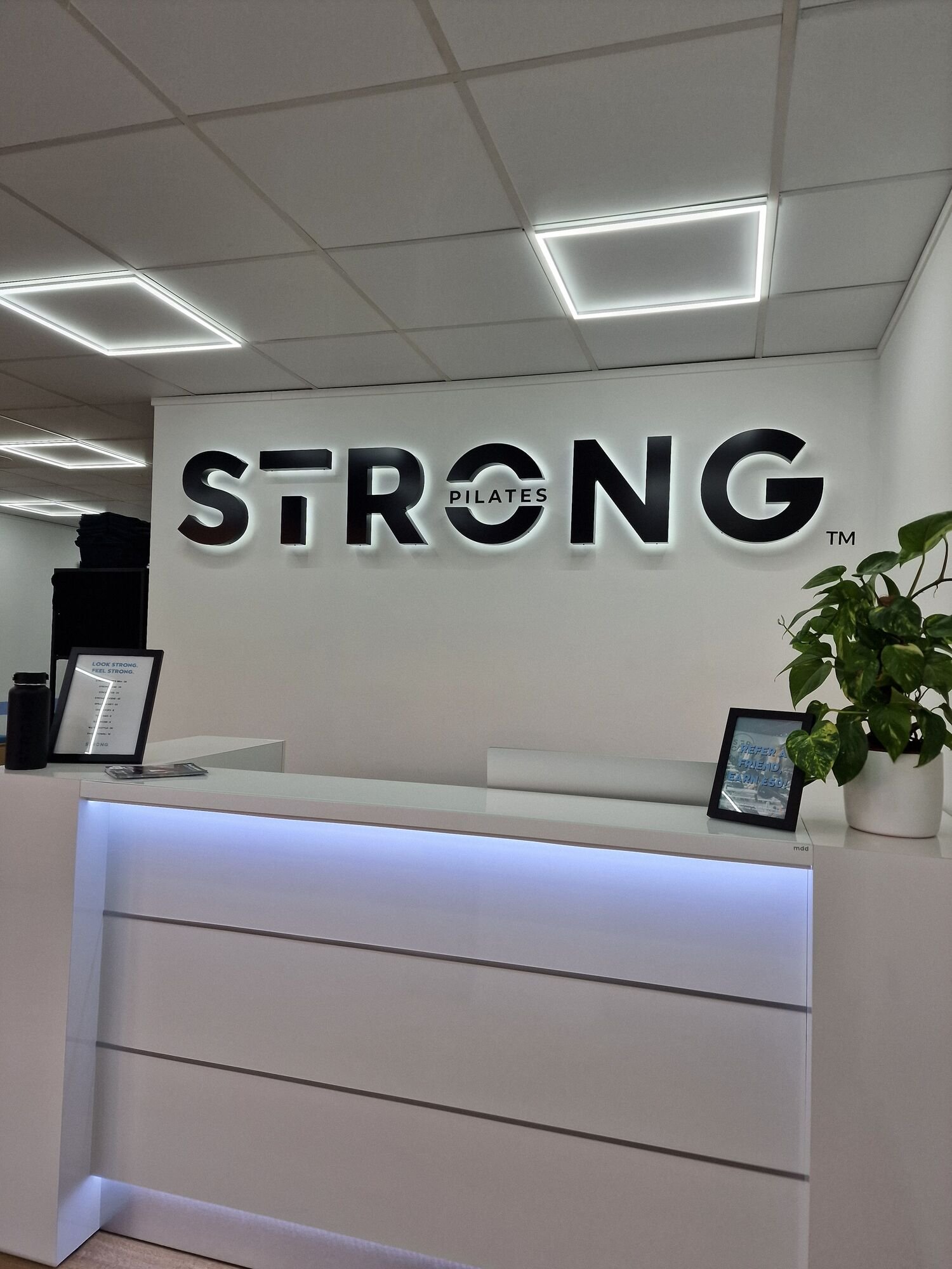Strong Pilates reception with an underlit desk and square LED frame panels in the ceiling, Leicester