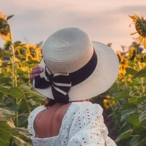 Close-up of a young woman with dark wavy hair, wearing a black leather jacket, resting her head on her hand in a contemplative mood outdoors.