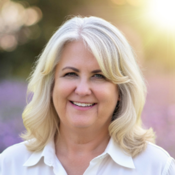 Emily Watson, a holistic therapist and grief counselor, is smiling in the sunlight.